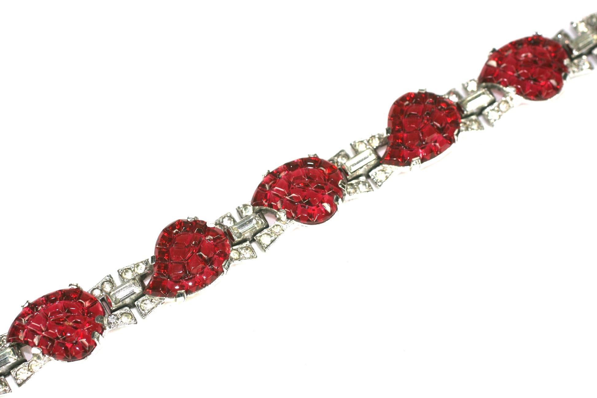 Mazer Art Deco faux ruby leaves invisibly set link bracelet of
rhodium plated base metal,  small crystal rhinestone pave,  and eight faux invisibly set calibre pressed ruby glass. The non-use of Sterling dates this to 1938  through 1942.
Excellent