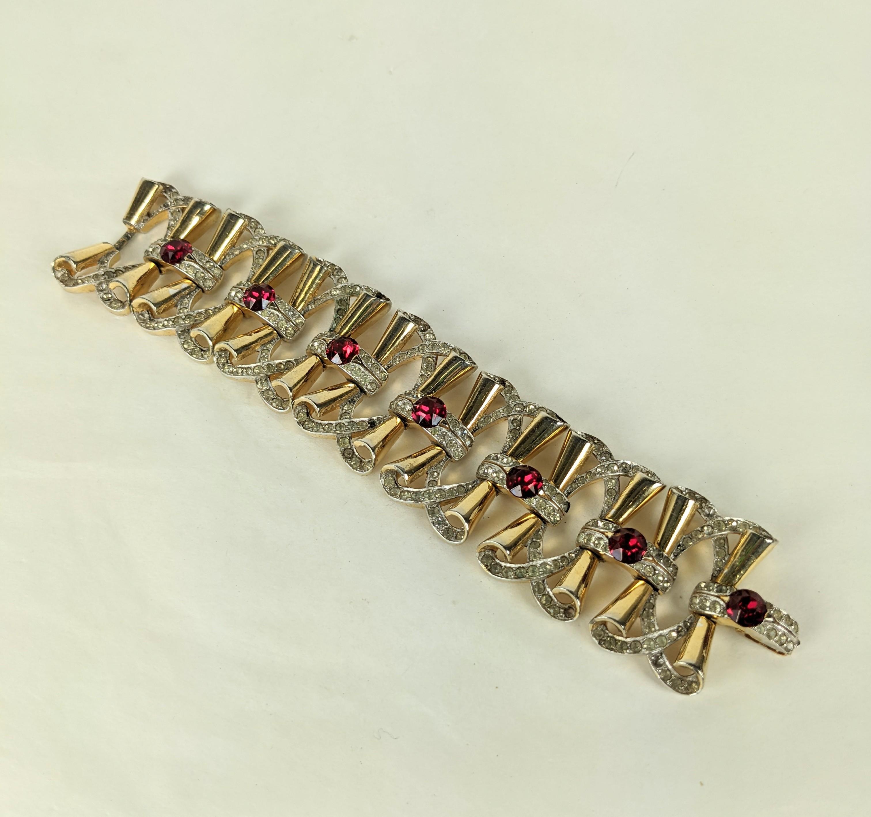 Mazer wide Retro link bracelet. Of rhodium plate base metal and yellow gold plate. Composed of overlapping linked retro bows with crystal pave rhinestone accents and large focal faux rubies.
Excellent Condition, Signed. Matching necklace available.