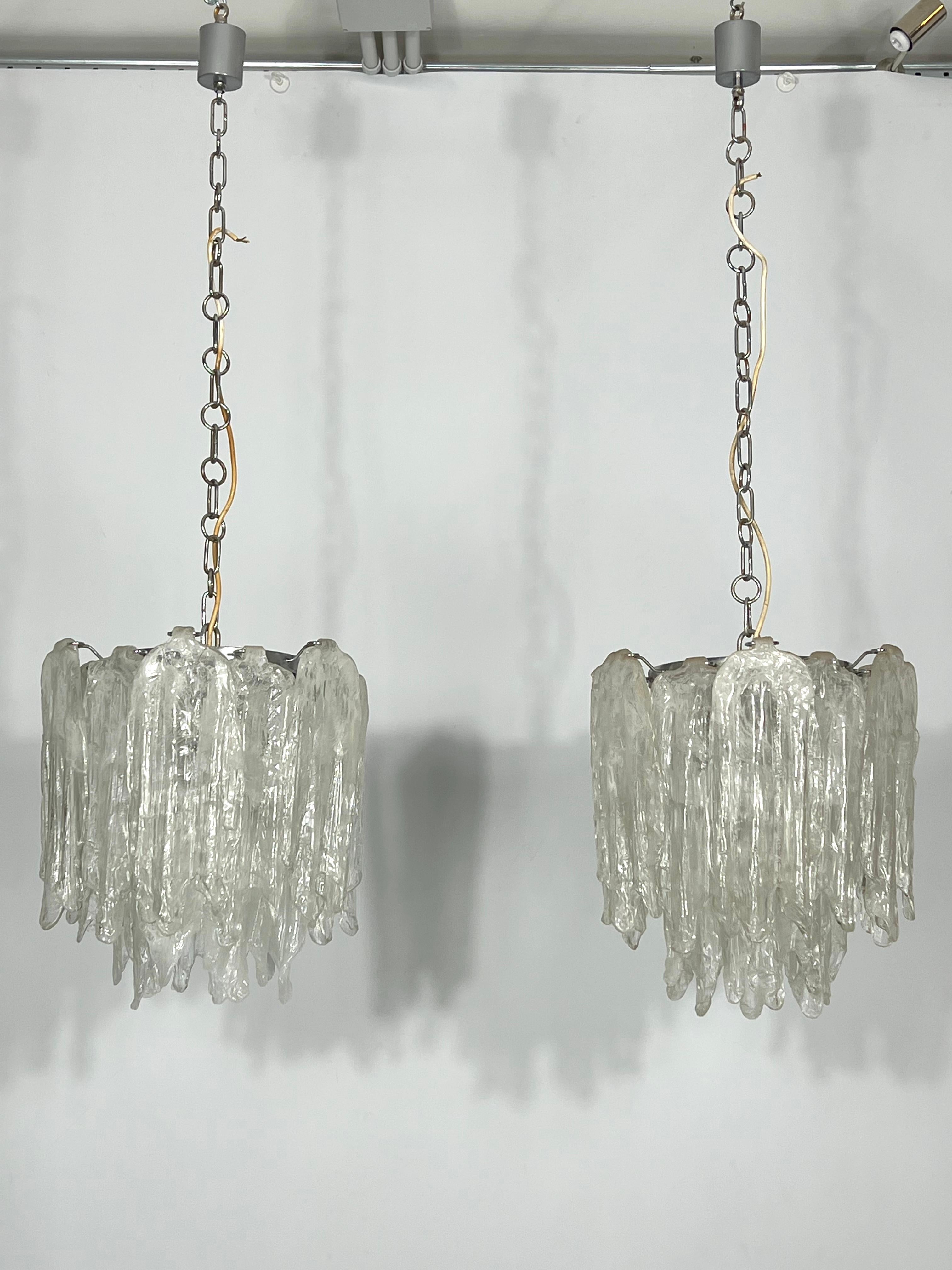 Great vintage condition for this pair of Mazzega chandeliers made from Murano glass type Ice and produced in Italy during the 70s. Each chandelier mounts 18 glasses. No missing parts, chips or cracks. Trace of age and use on the metal structure.