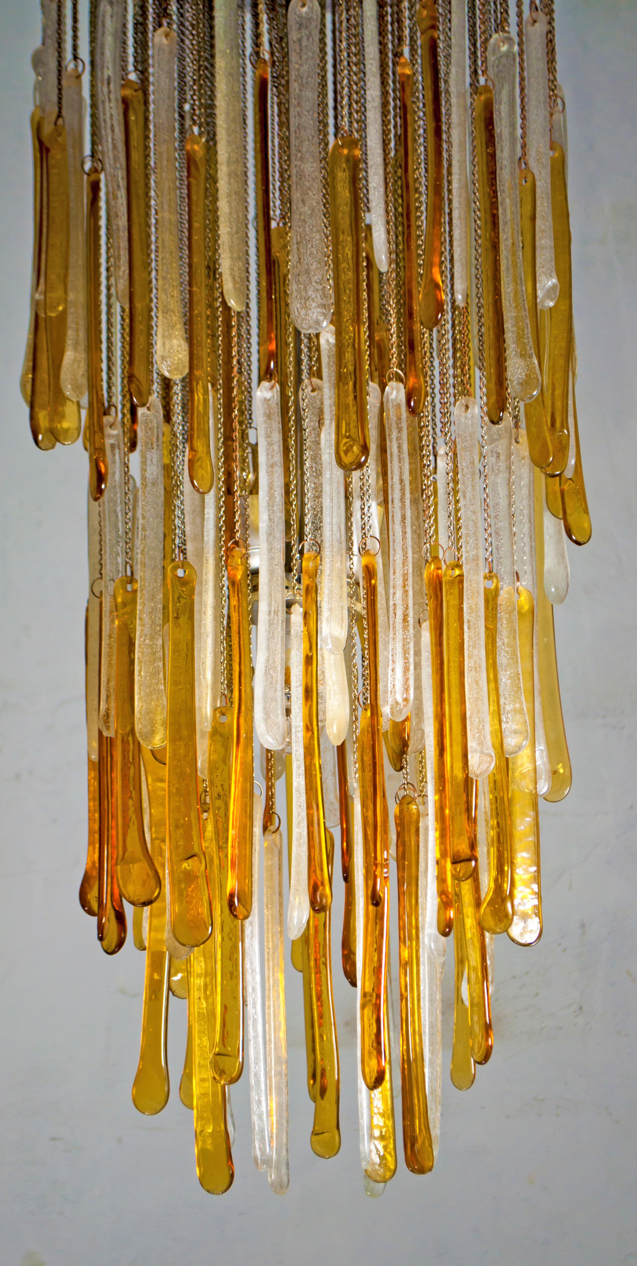 This Murano glass chandelier was produced by Mazzega in Pulegoso glass, the structure is in chromed metal.
Amber and transparent color, Italy, 1960s.

The historic glassworks Mazzega IVR was the architect, since the mid-1950s, of a profound artistic
