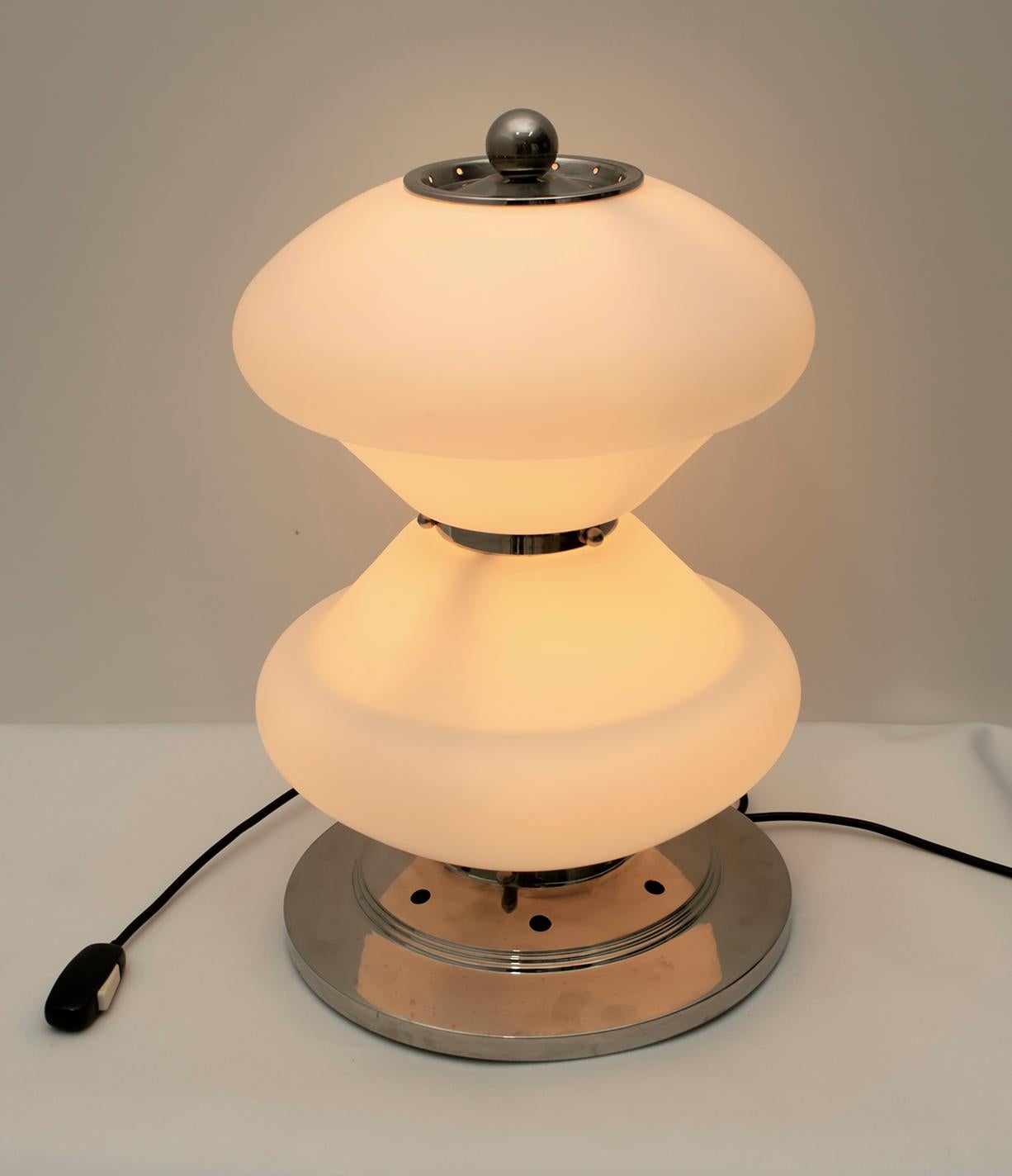 Cette lampe de table, avec une base en métal chromé et du verre de Murano 