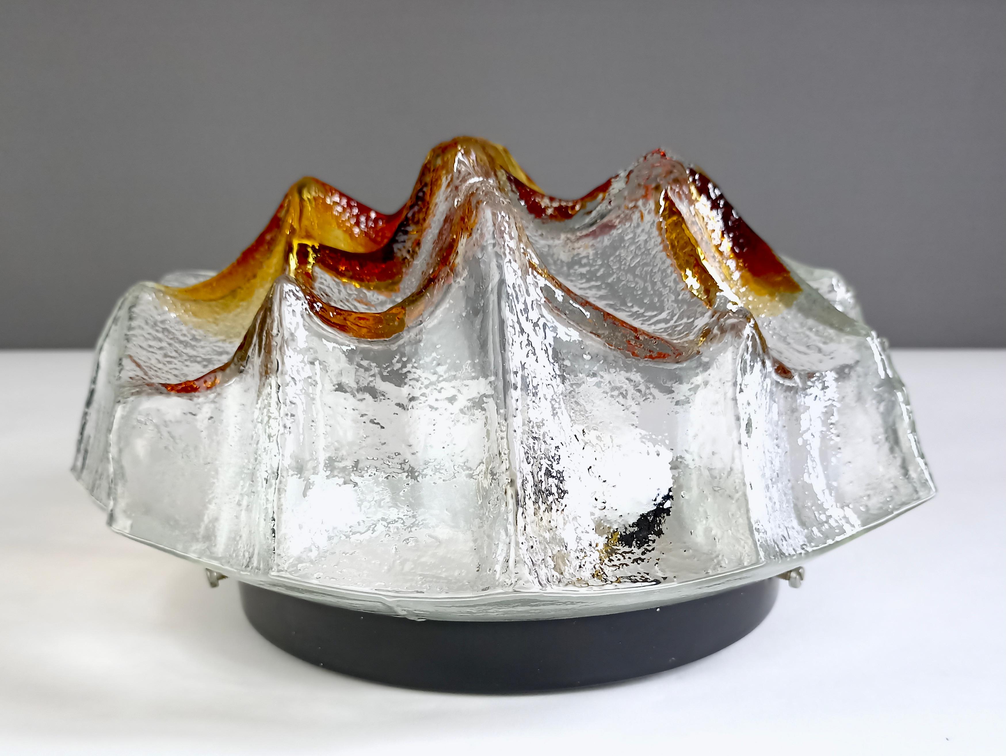 Italienische einflammige Einbau-/Wandleuchte aus dickem Murano-Kunstglas aus den 1960er Jahren, die Mazzega zuzuschreiben ist. 
Der Lampenschirm ist aus klarem Glas und wurde beim Gießen mit orange-bernsteinfarbenem Glas angereichert. Es hat eine