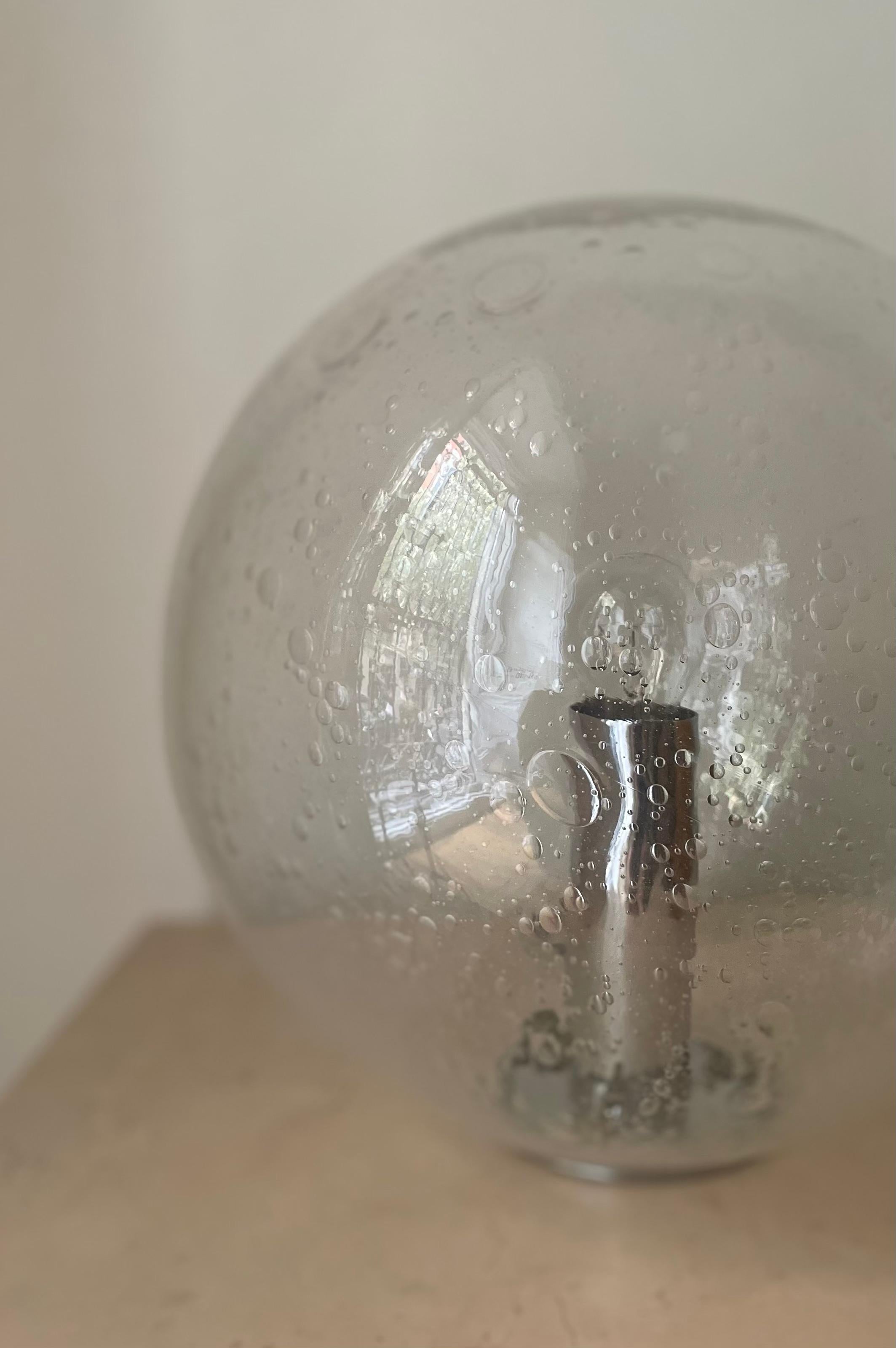 Murano chandelier manufactured by Mazzega with the technique Bullicante and chrome base. Italy, 1950s.

Height: 36cm
Diameter: 35cm
*1 bulb*

The factory A.V. Mazzega was founded in 1946 in Murano, the birthplace of Venetian art glass. From its