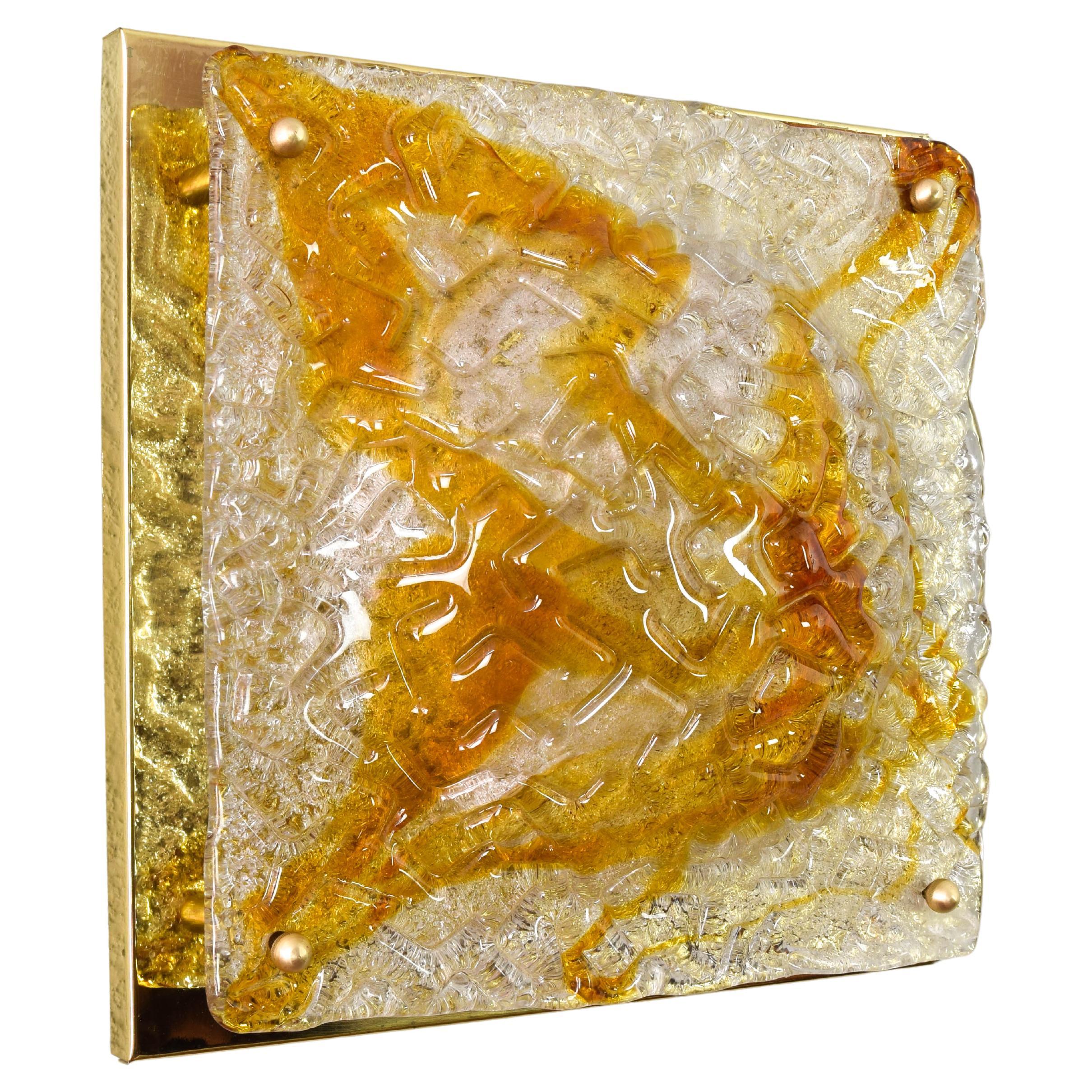 Stunning Murano glass Flushmount in relief on brass plate produced by Mazzega in Italy in the 1960's.
The large Murano glass plate in a clear and amber caramel color is very thick and presents relief and markings that give an effect of warm light