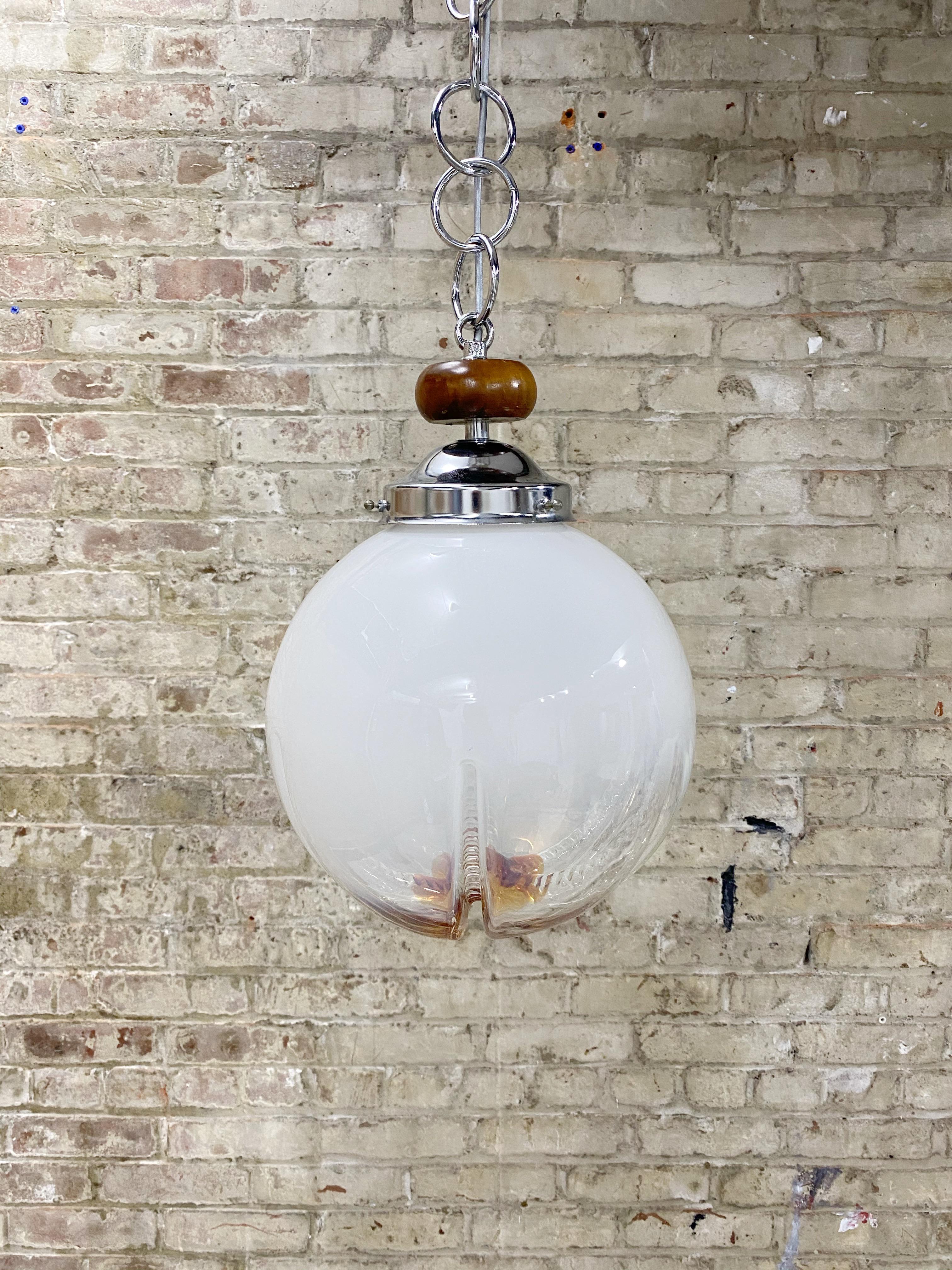 Fabulous Mazzega Murano globe pendant light. Milky colored glass with ombré effect to orange amber color. Globe shape with abstract blown glass effect. Wood detail. Full circle chain links, 16” long. Includes ceiling canopy. Professionally rewired