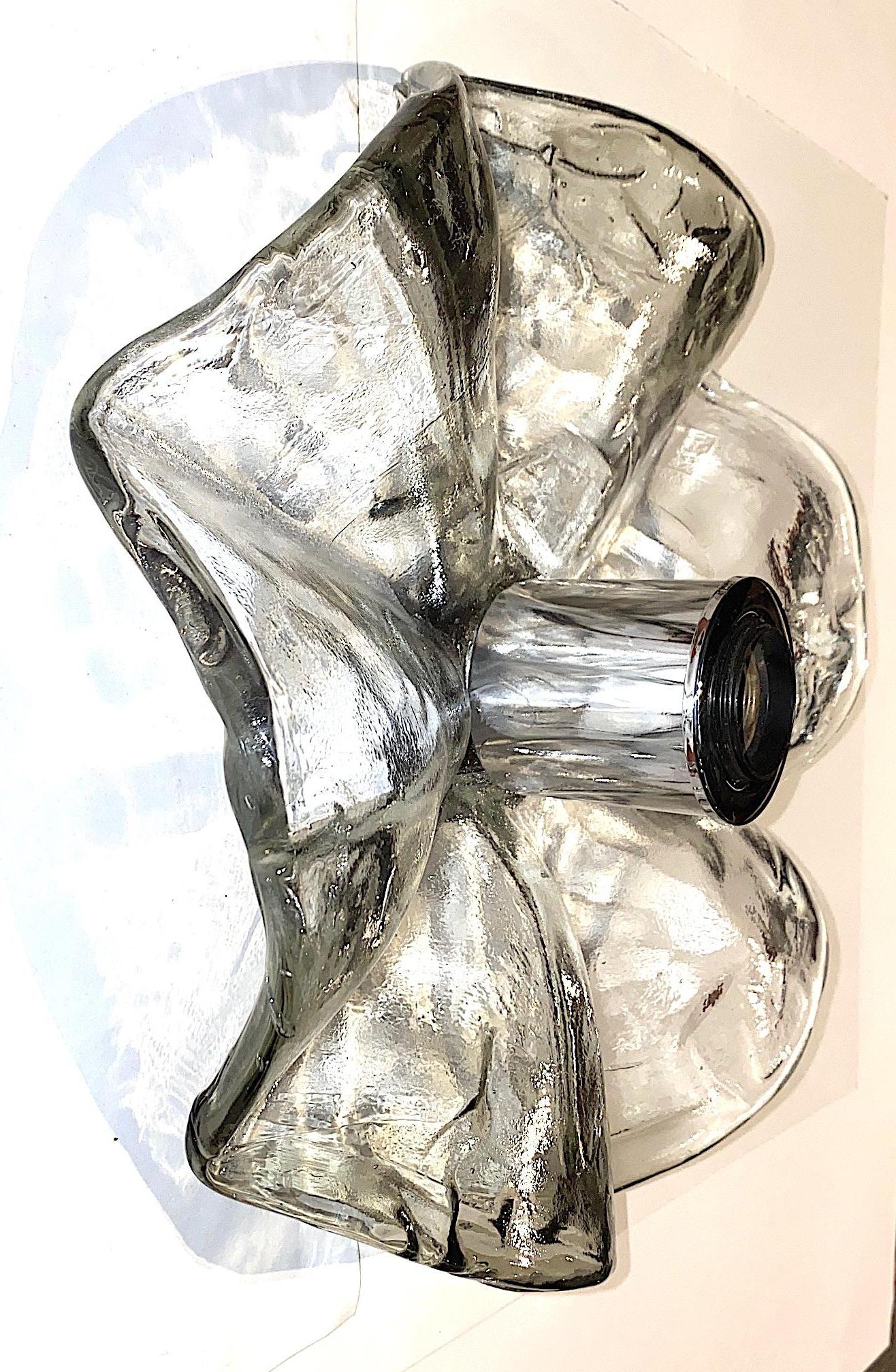 A lovely scallop flower form single sconce by Italian lighting company Mazzega, circa 1970. The hand formed glass disk is 13 inches in diameter has a scallop three dimensional design. The central socket has a chrome cover. The wall light may also be
