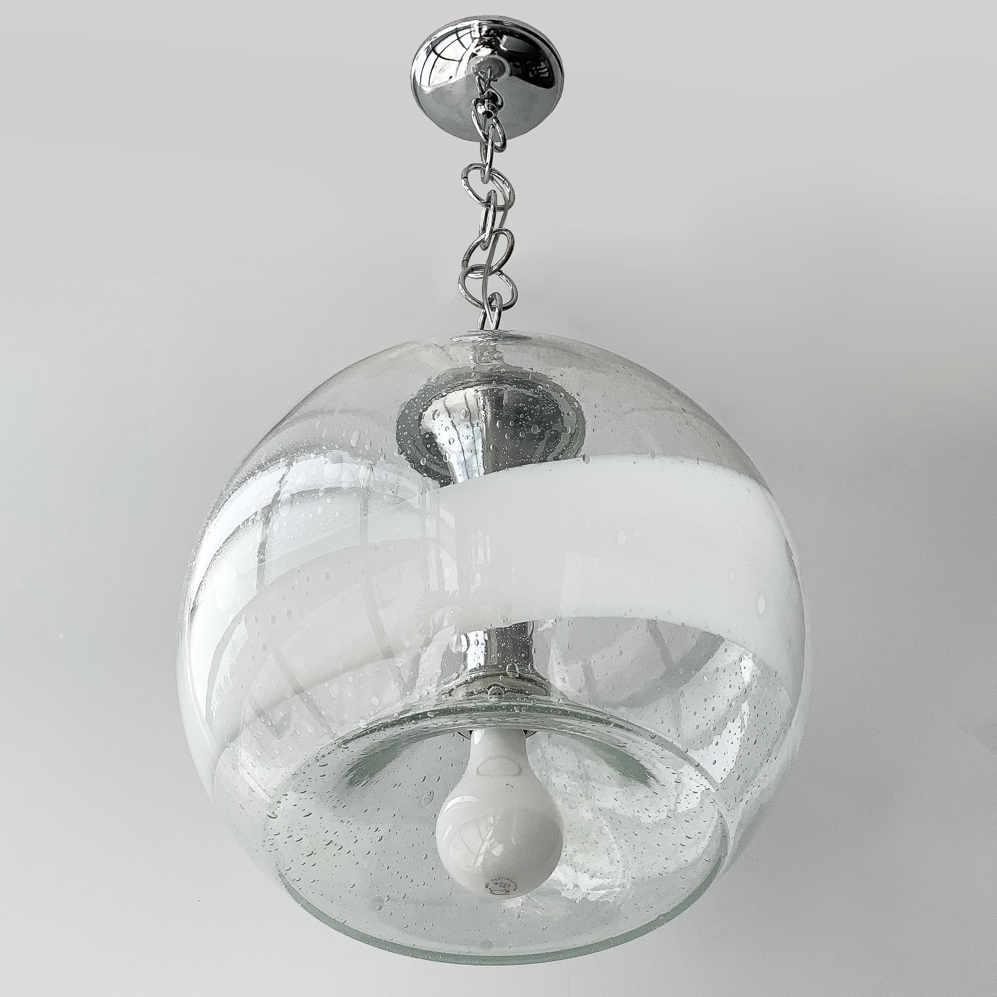 Italian globe pendant chandelier in clear bubbled glass with a wide band of white by Mazzega, circa 1970s. Sphere shaped Murano glass with inverted bottom and recessed socket. Takes one standard base light bulb. Chrome cylinder shaft, cap, circular