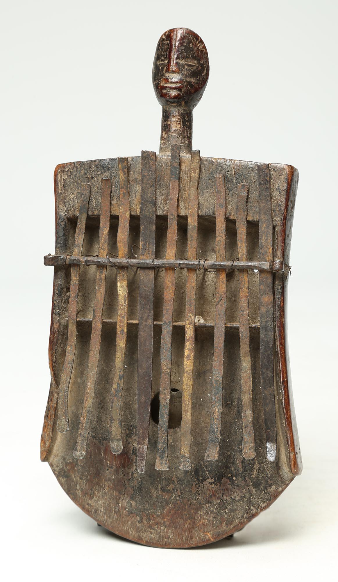 Mbira oder Sanza (früher als Daumenklavier bekannt), aus geschnitztem Holz mit Metalltasten. Auf der Oberseite befindet sich ein subtil geschnitztes menschliches Gesicht mit toller Patina. Sie wurde Ende des 19. bis Anfang des 20. Jahrhunderts in