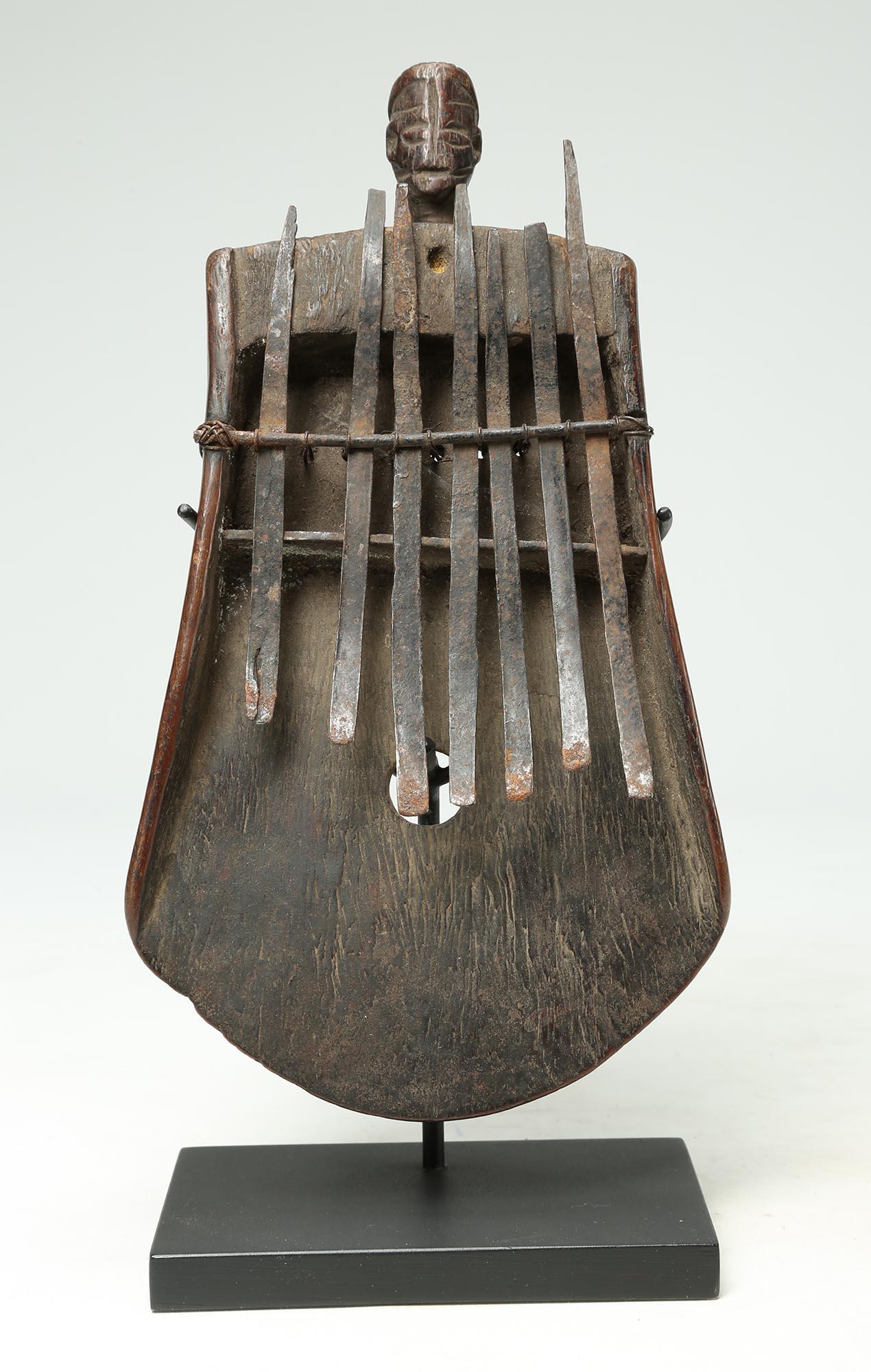 Carved worn wood Mbira or Sanza (once known as a thumb piano) with metal strikers from the early period in the Congo, Central Africa. On top is a subtly carved human face with great wear and patina from handling. Late 19th to early 20th century. The
