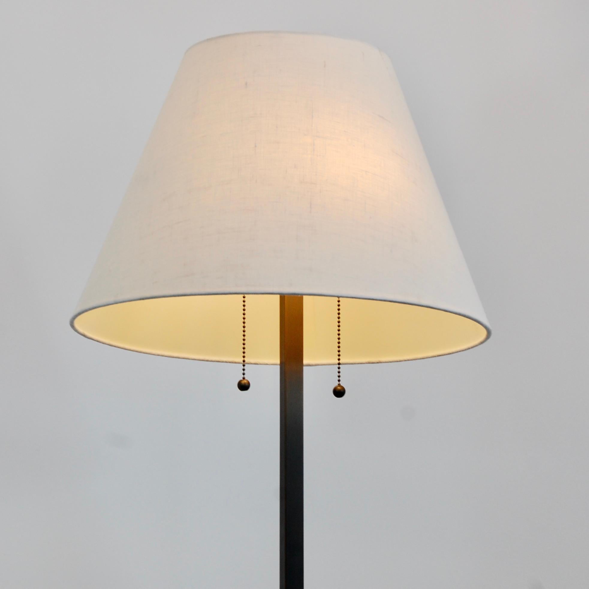 Elegant all-brass X-based mid-century modern inspired floor lamp. Detailed with a fabric shade, two pull switches from two E26 medium based sockets. Ready to be used in the USA. Finish: patinated brass. 
Measurements:
Height: 52” 
Diameter