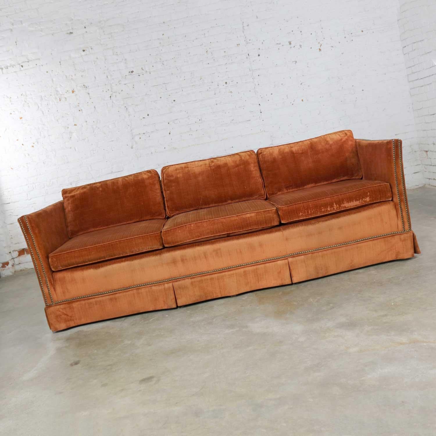 Handsome burnt orange velvet mid-century Hollywood Regency style tuxedo sofa with bronze tone nailhead detail. There is no tag, but it is very nicely made. It is in great usable vintage condition and has been recently cleaned. The awesome original