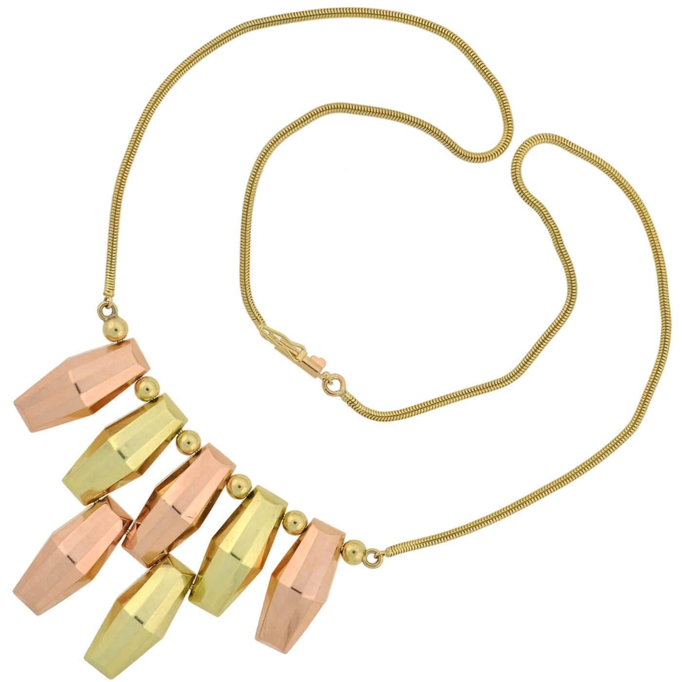 A fabulous two-tone necklace from the Retro (ca1940) era by M.C. MOSSALONE! Crafted in 14kt yellow and rose gold, this bold piece has an eye-catching and geometric design which hangs from a gold snake chain. A row of barrel-shaped links hang