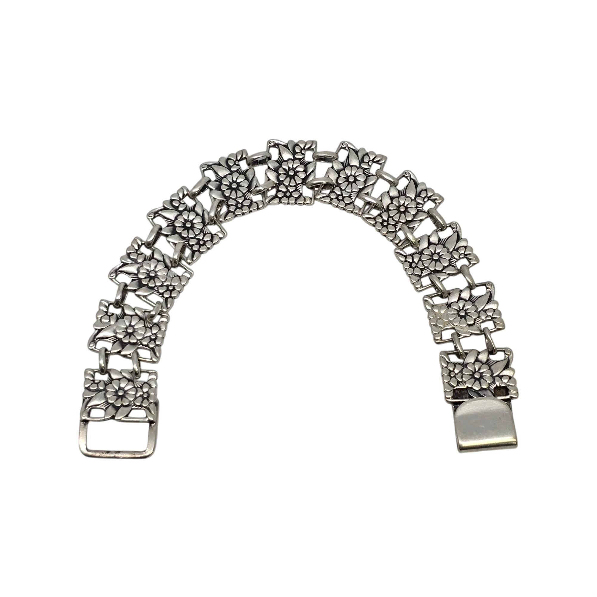 Bracciale a maglie con pannello floreale in argento sterling di McClelland Barclay.

Questo dolce braccialetto è caratterizzato da maglie rettangolari a pannello floreale traforato. Chiusura a gancio.

Pesa circa 24,8g, 15,9dwt.

Misura circa 7