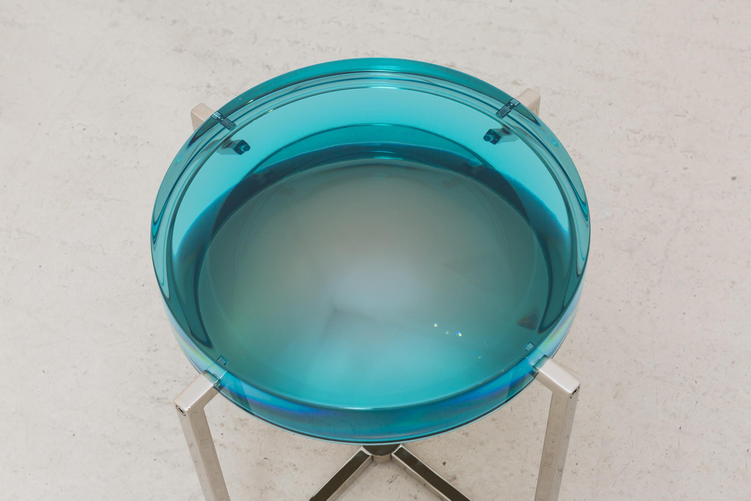 McCollin Bryan lens table in turquoise. Resin top backed by acrylic mirror on nickel base with four legs.