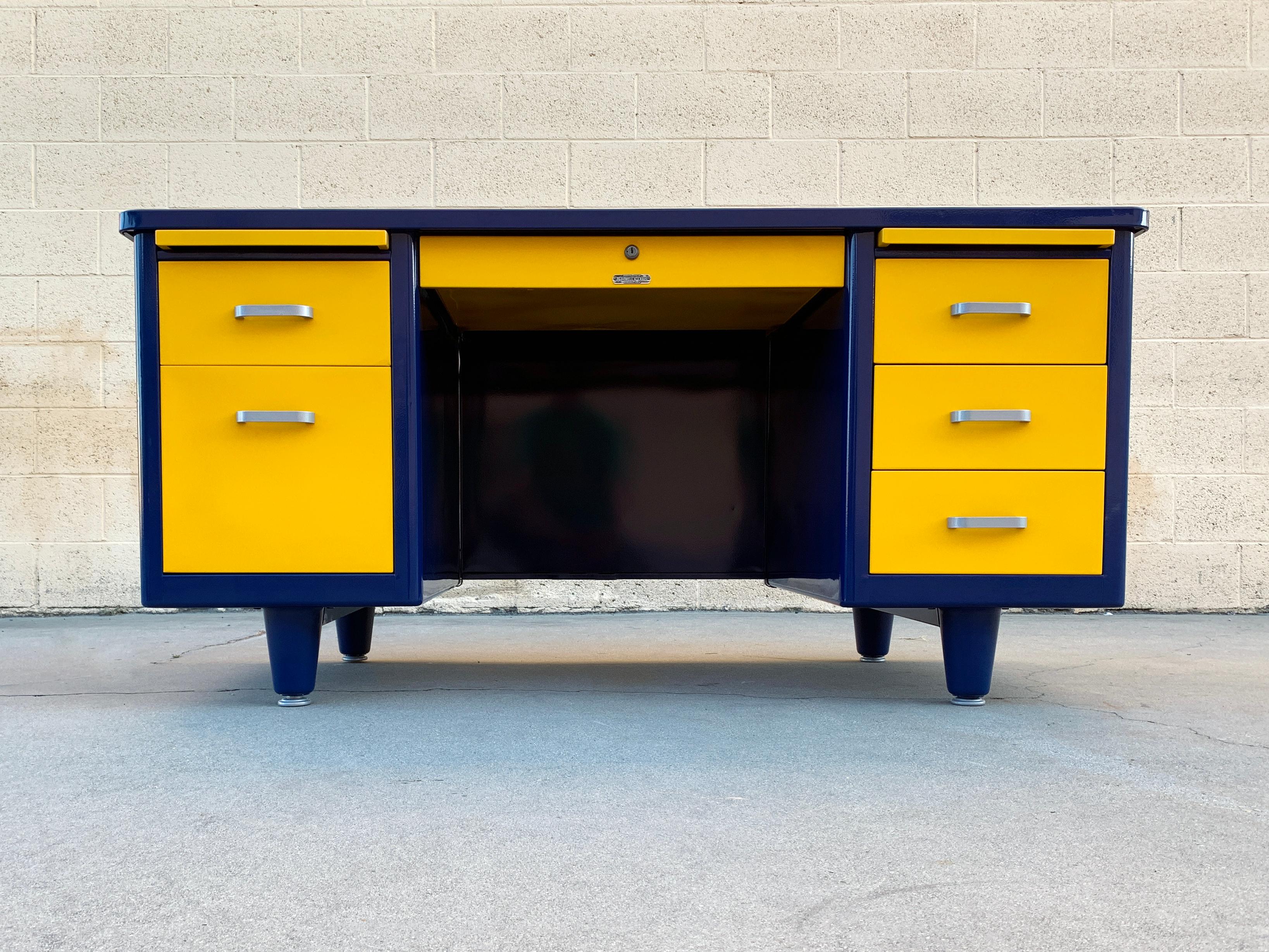 1960s Classic tanker refinished in gloss midnight blue (BL20) and yellow ochre (RAL 1003), Go Rams! This double pedestal steel desk features utility drawers, filing drawer, locking stationary drawer and letter trays. All original aluminum hardware,
