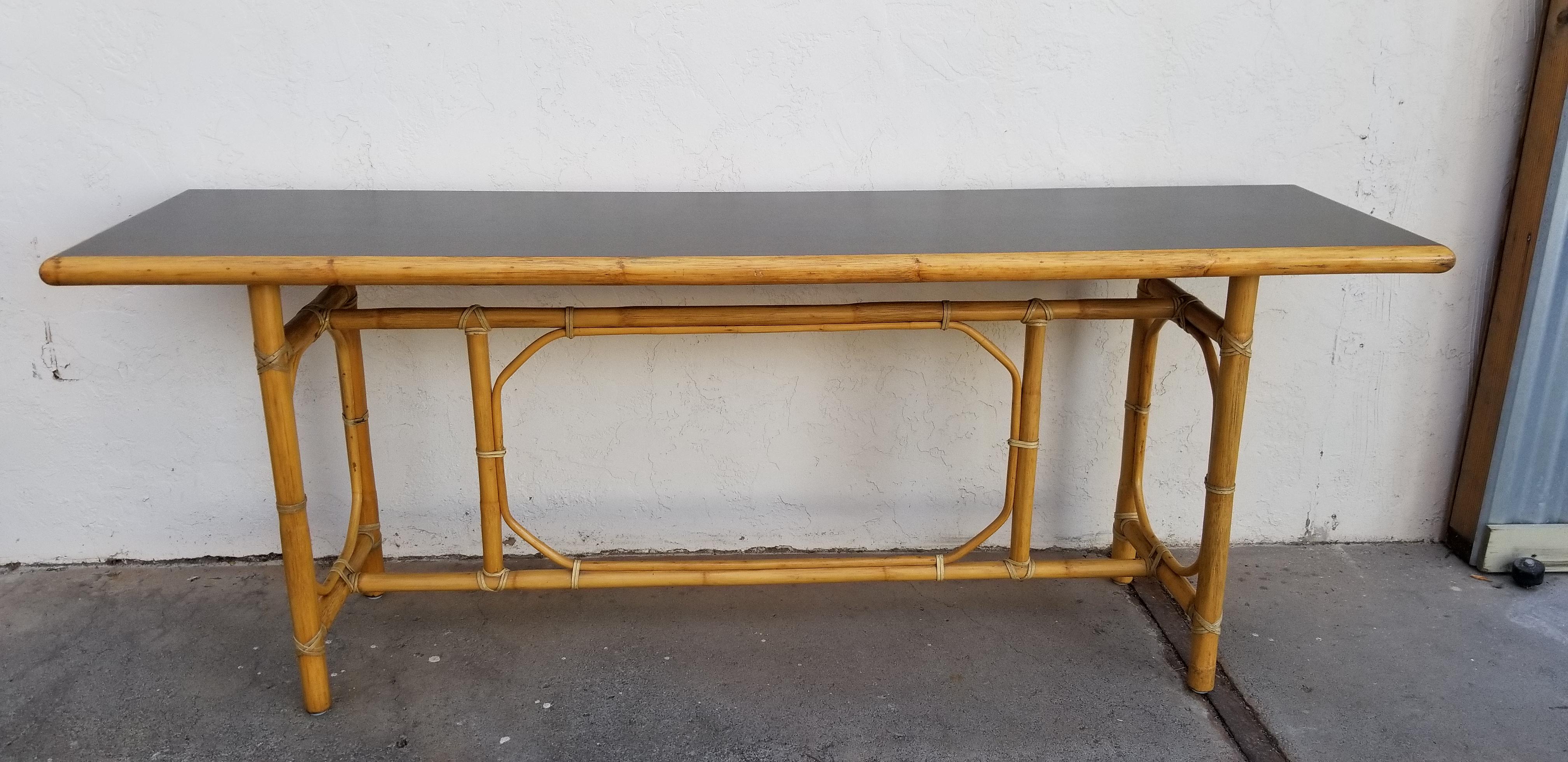 Finely crafted console or sofa table by John McGuire of San Francisco, California. Dark green leather inset top with bamboo frame and leather bindings. Very good original vintage condition retaining brass McGuire label. Patented joinery creates a