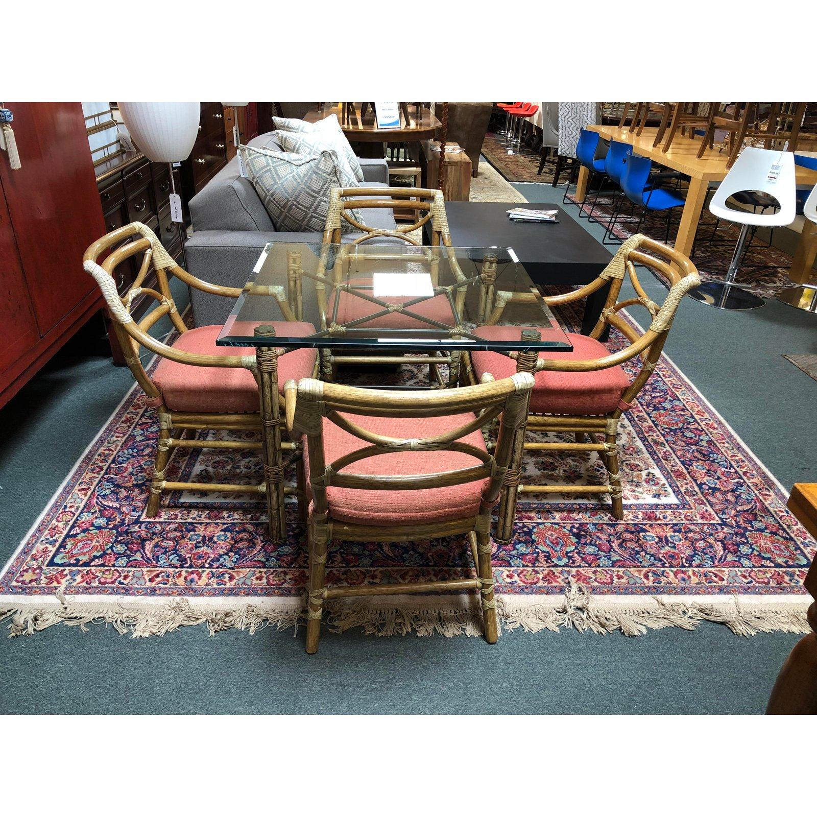 A set of four Regency armchairs by McGuire. Beautifully constructed of rattan accented with raw hide leather straps, the chairs work for dining or for other seating arrangements. The slightly rounded back adds to comfort and beauty. Loose seat