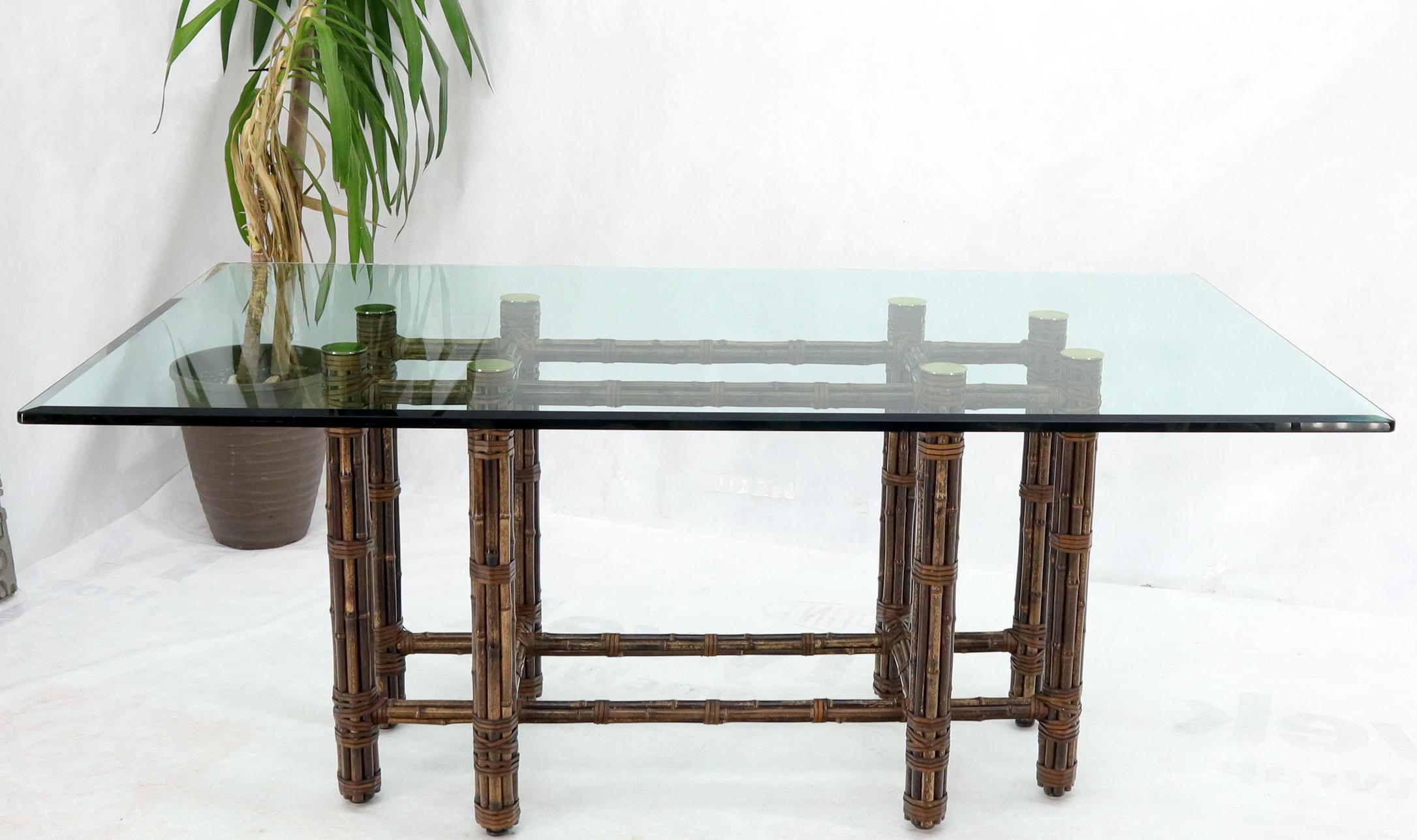 Massive thick glass top bamboo and leather base dining table attributed to McGuire.