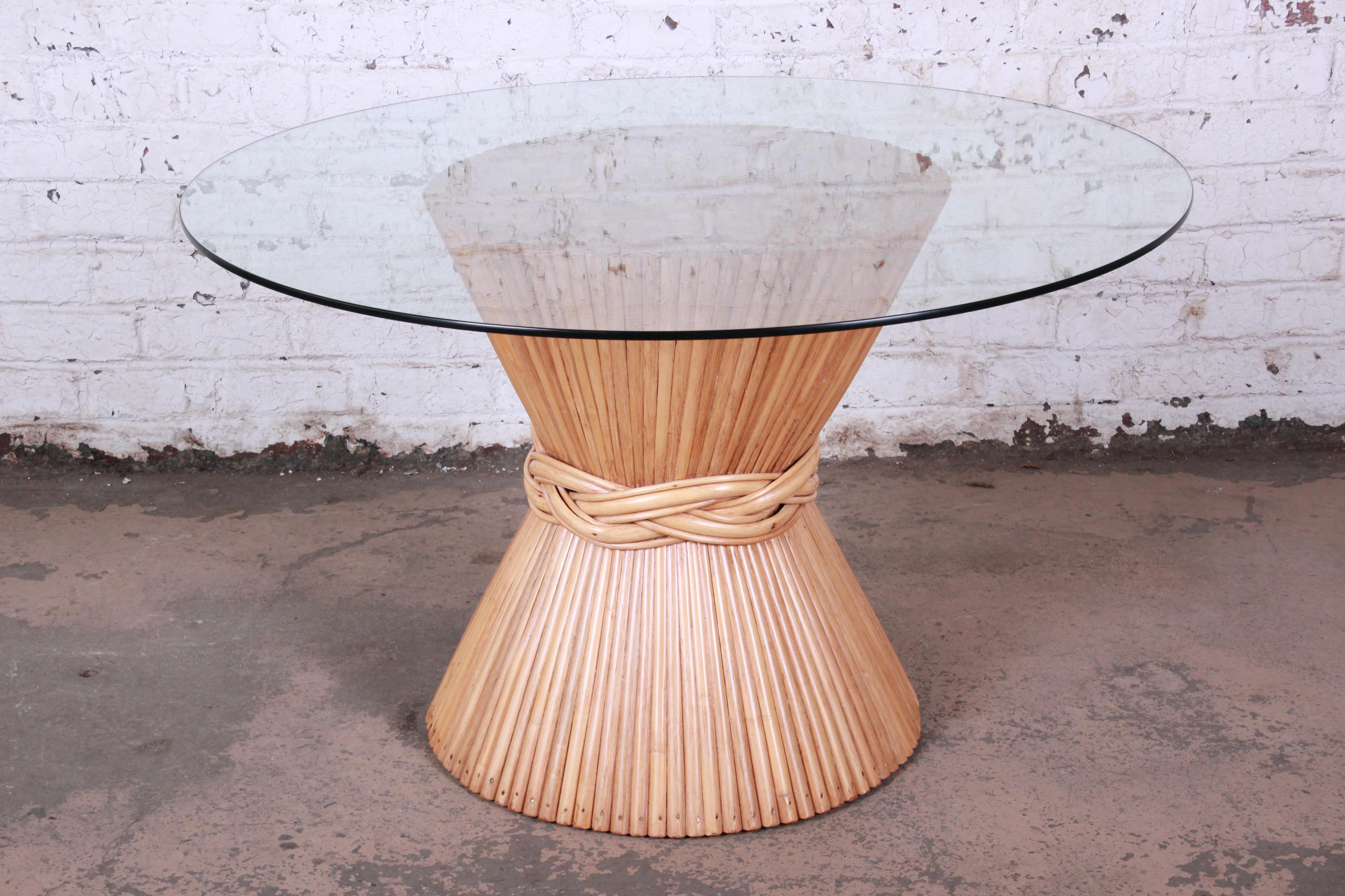 Offering a very nice McGuire bamboo pedestal dining table with a round glass top. The table has a unique ribbon weave design at the center of a sheaf of wheat base. The base has been re-lacquered giving it a nice fresh look while maintaining its