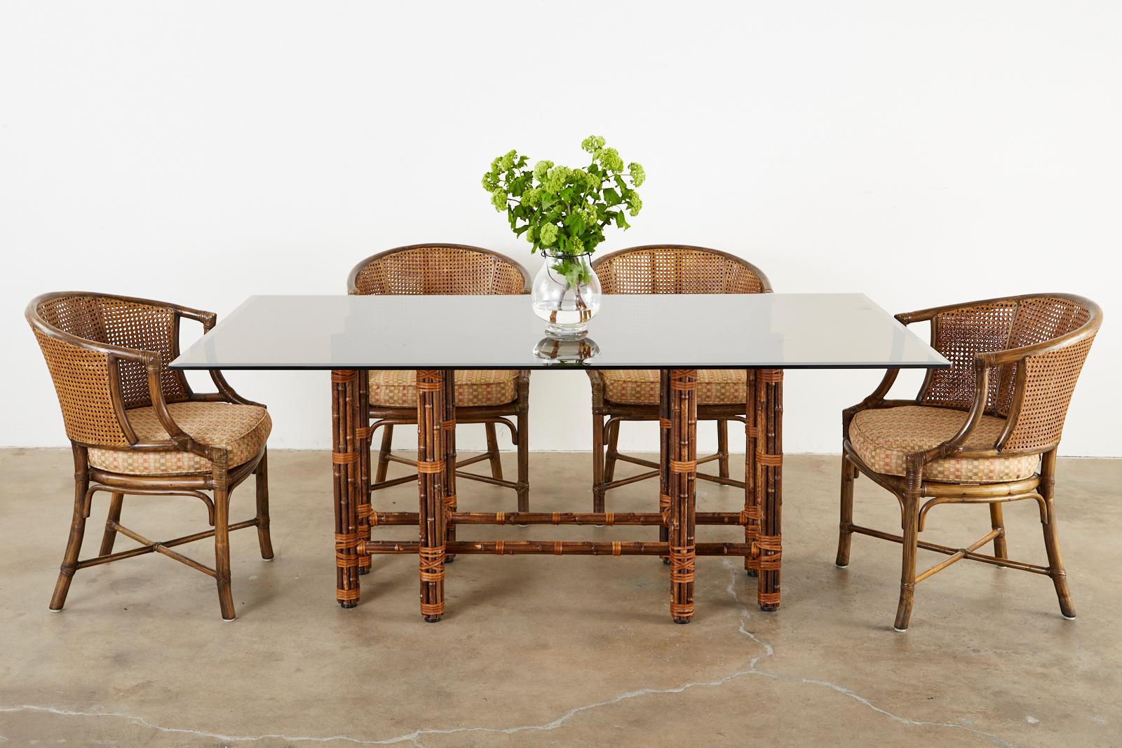 Genuine McGuire bamboo rattan glass top dining table made in the California organic modern style. The table features a rare rectangular shaped iron frame painted golden gate orange for McGuire authenticity. It is covered with bamboo poles lashed