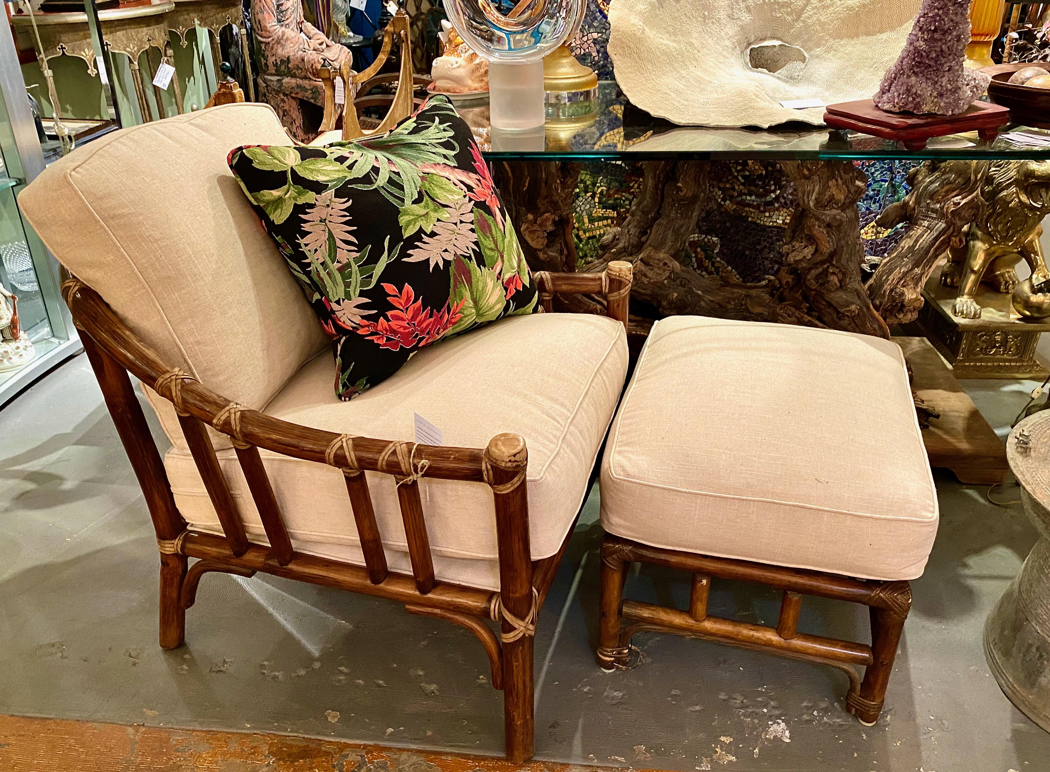 This an iconic arm chair and associated ottoman designed and manufactured by renown San Francisco-based McGuire furniture company. The chair retains its McGuire metal tag (currently obscured by the strap cover). The associated ottoman is attributed
