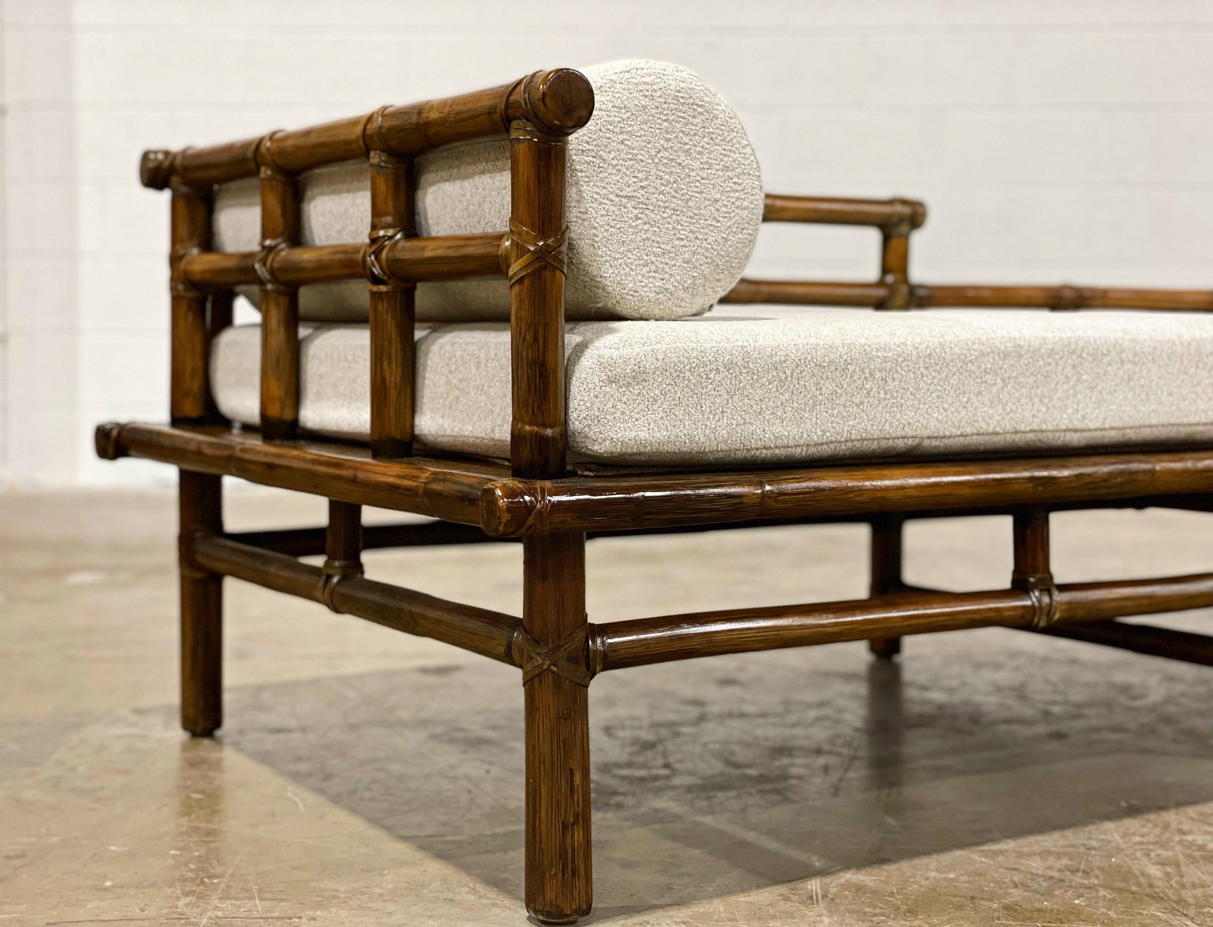 Vintage mid-century bamboo rattan daybed chaise lounge by McGuire, San Francisco circa 1965. Hand-crafted in the California organic modern style - this piece features a sturdy rattan and oak frame with leather rawhide joinery and end caps. The back