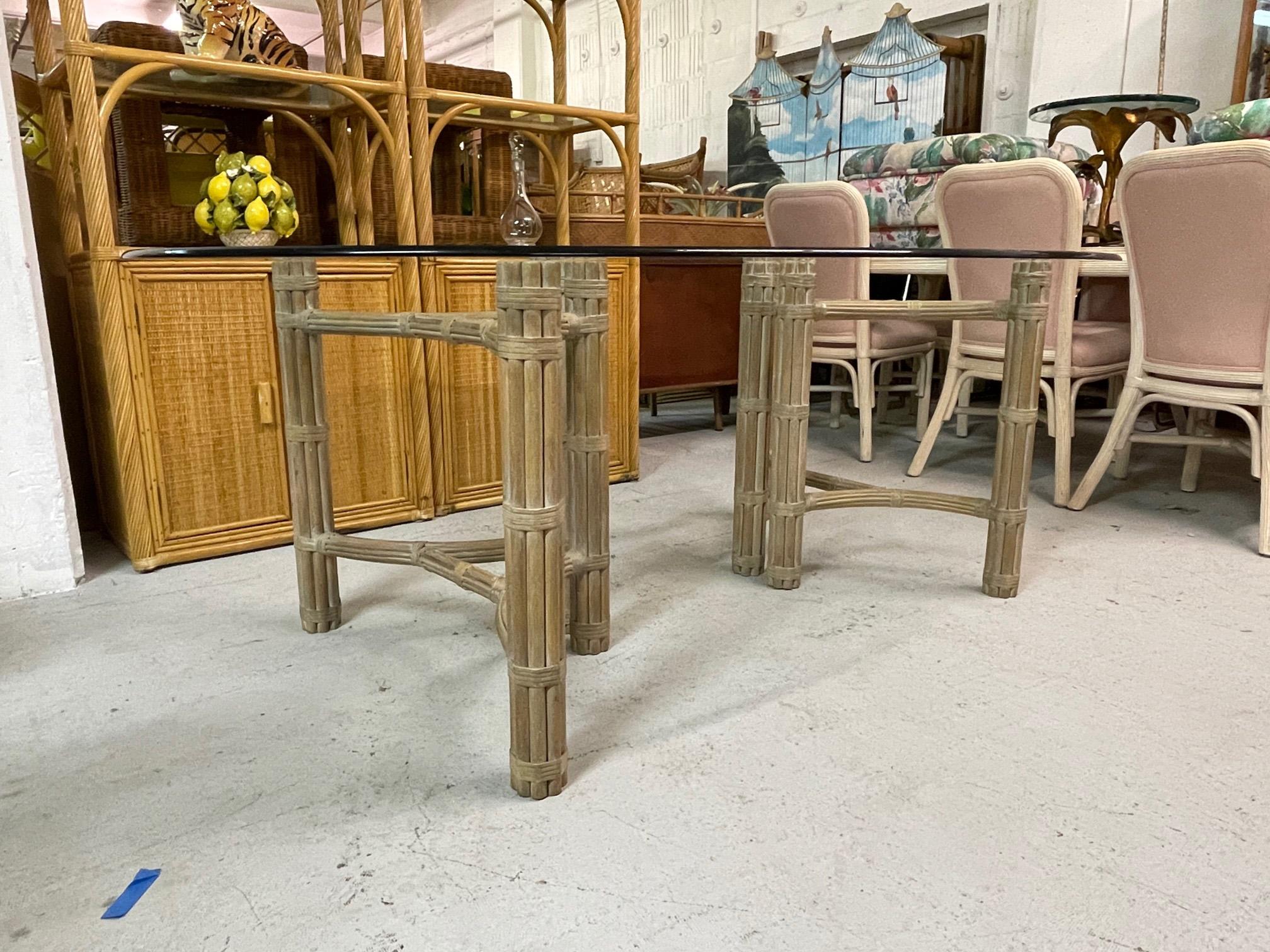 Double pedestal dining table by McGuire features a steel core sheathed in rattan and a glass top. Good condition with minor imperfections consistent with age. May exhibit scuffs, marks, or wear, see photos for details. Can be shipped without glass