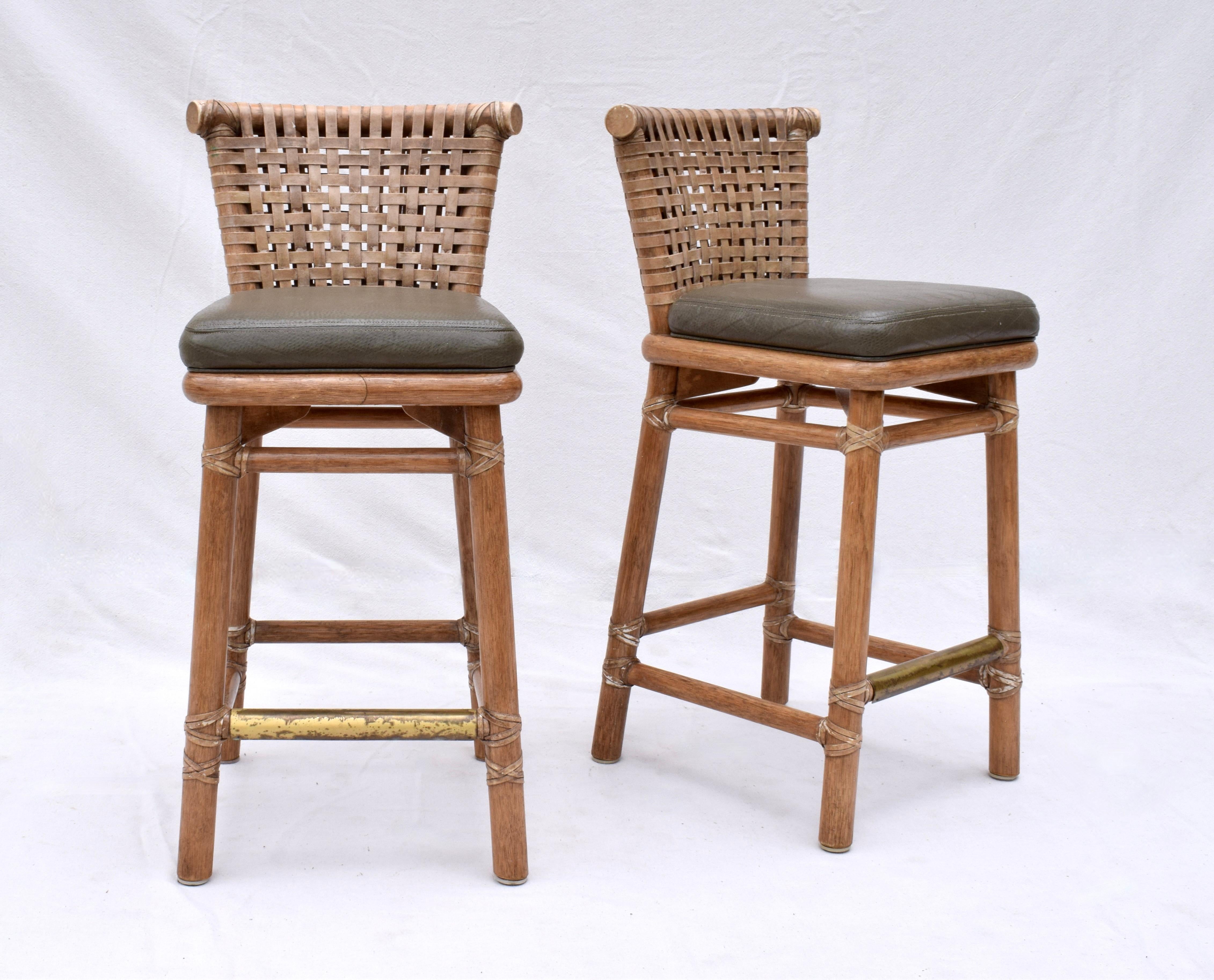 A pair of McGuire solid Oak barstools with leather seats, laced rawhide leather backs, subtly curved back rails and solid brass foot supports. These vintage beauties are quite substantial in weight & quality. Each chair has original McGuire San
