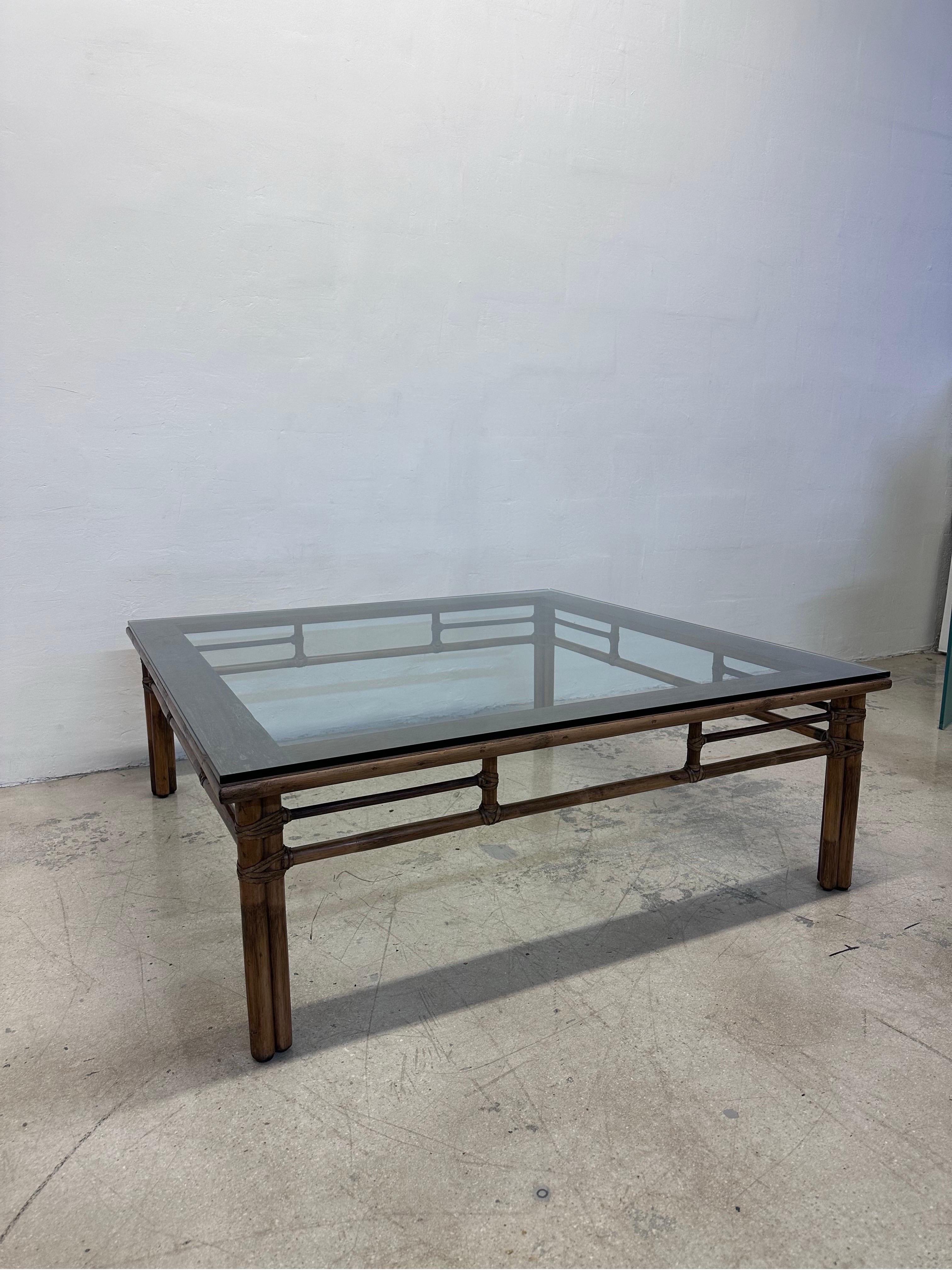 Large mid-century rattan and glass top coffee or cocktail table with raw hide straps by McGuire San Francisco.  

The glass is 47” squared and is 1/2” thick with a flat polished edge and has a slight bevel.
