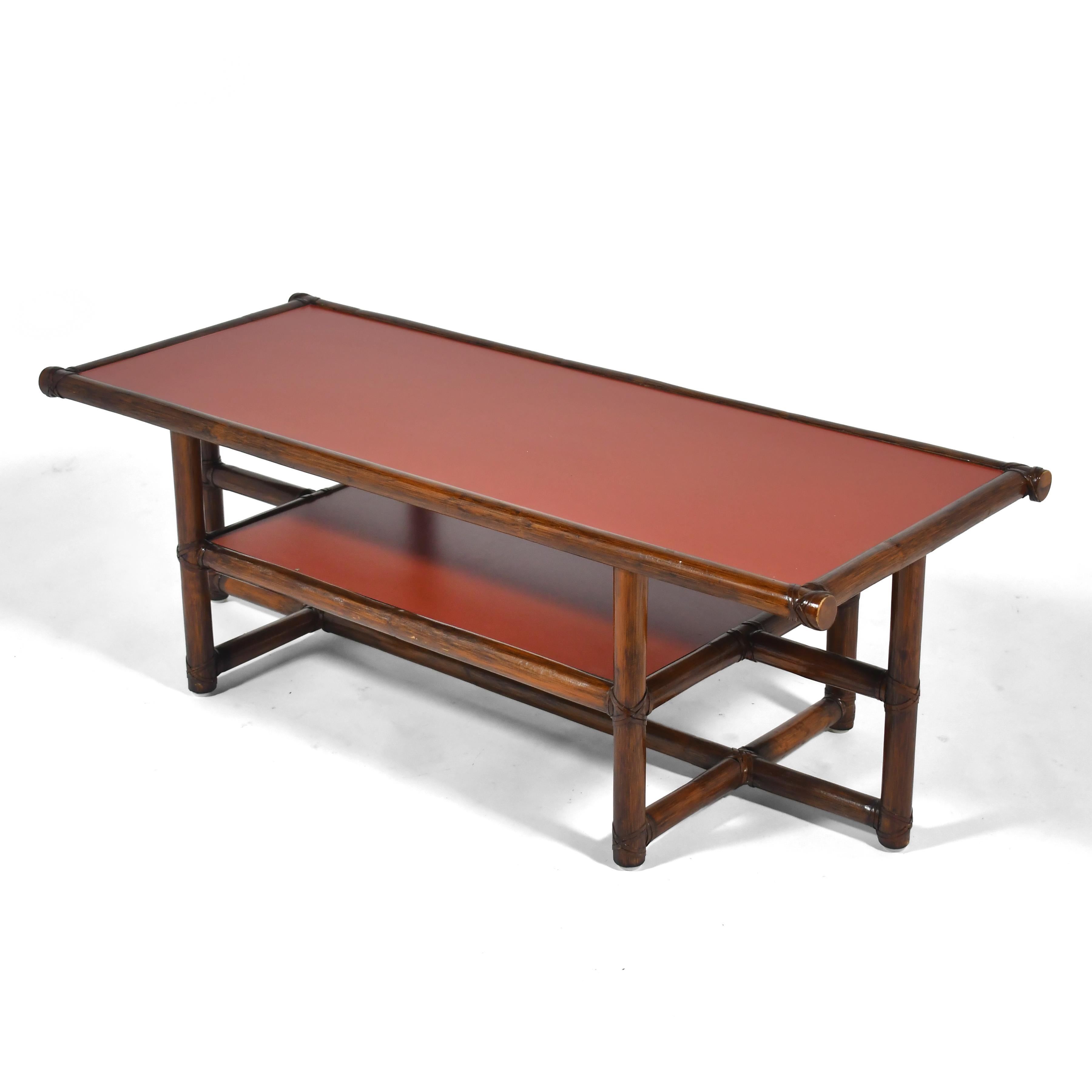This handsome early design by Elinor McGuire for her company McGuire of San Fransisco has a top and shelf supported by a rattan frame joined by McGuire's trademarked rawhide method. The tops are of hard-wearing mica in a beautiful bittersweet