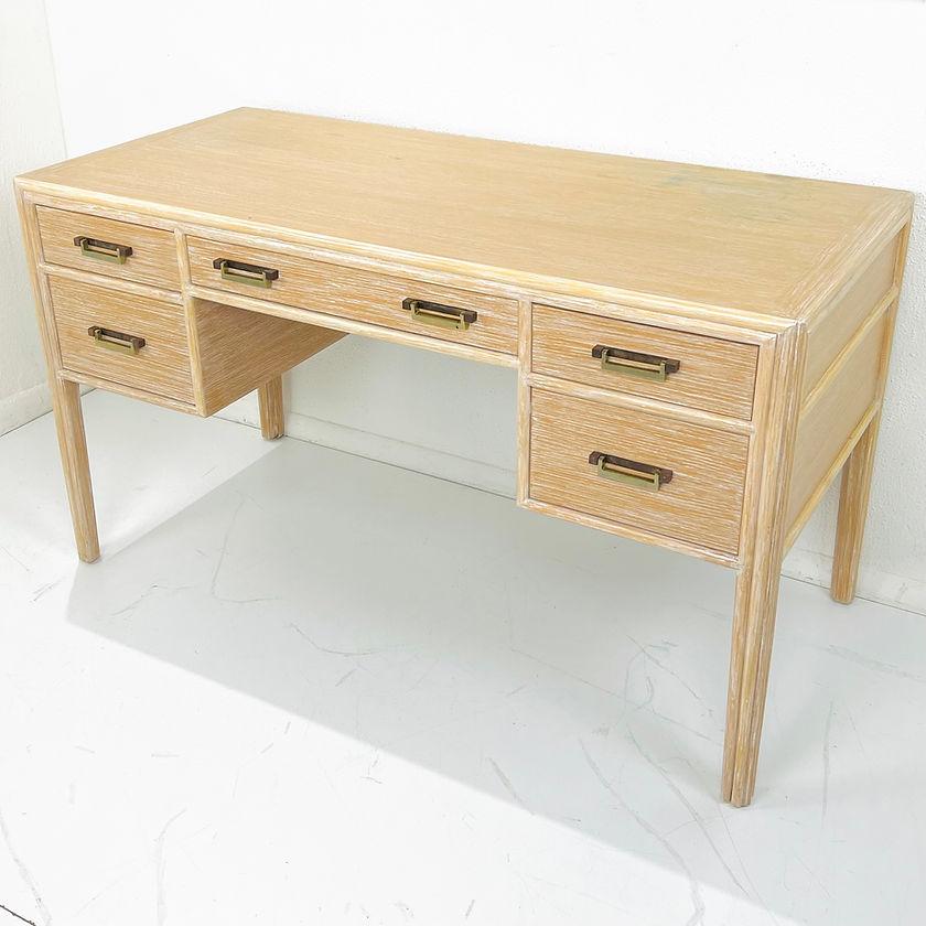 Mid-century modern desk with light wash color that highlights the woodgrain and brass drawer drop handles. The neutral finish makes this desk more contemporary than its dark brown and dark metal counterparts. Two left and right drawers with one
