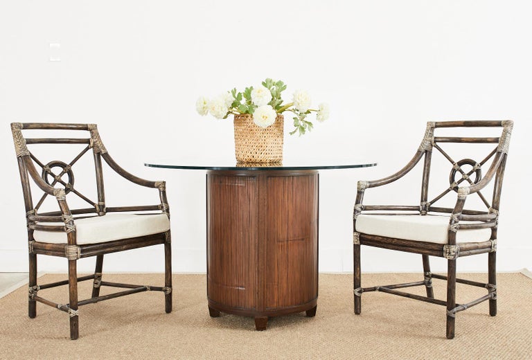 Handsome round pedestal dining table or center table made by McGuire. The table features a cylindrical form with bamboo rattan veneer on the sides and top in a dark rich finish. Made in the California organic modern style topped with a round pane of