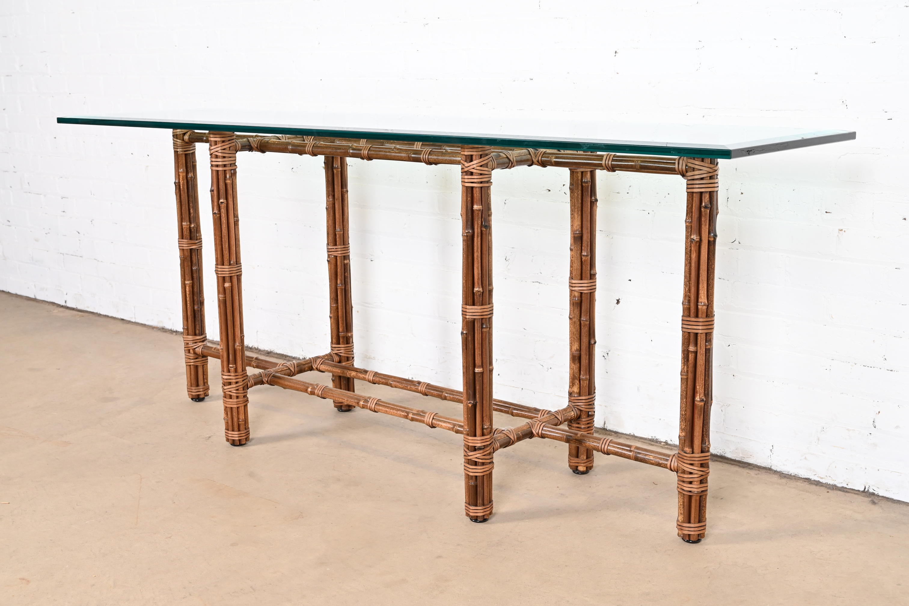 An exceptional midcentury Organic Modern console table

By McGuire

USA, circa 1970s

Bamboo, rattan, and leather base, with thick beveled glass top.

Measures: 71.75