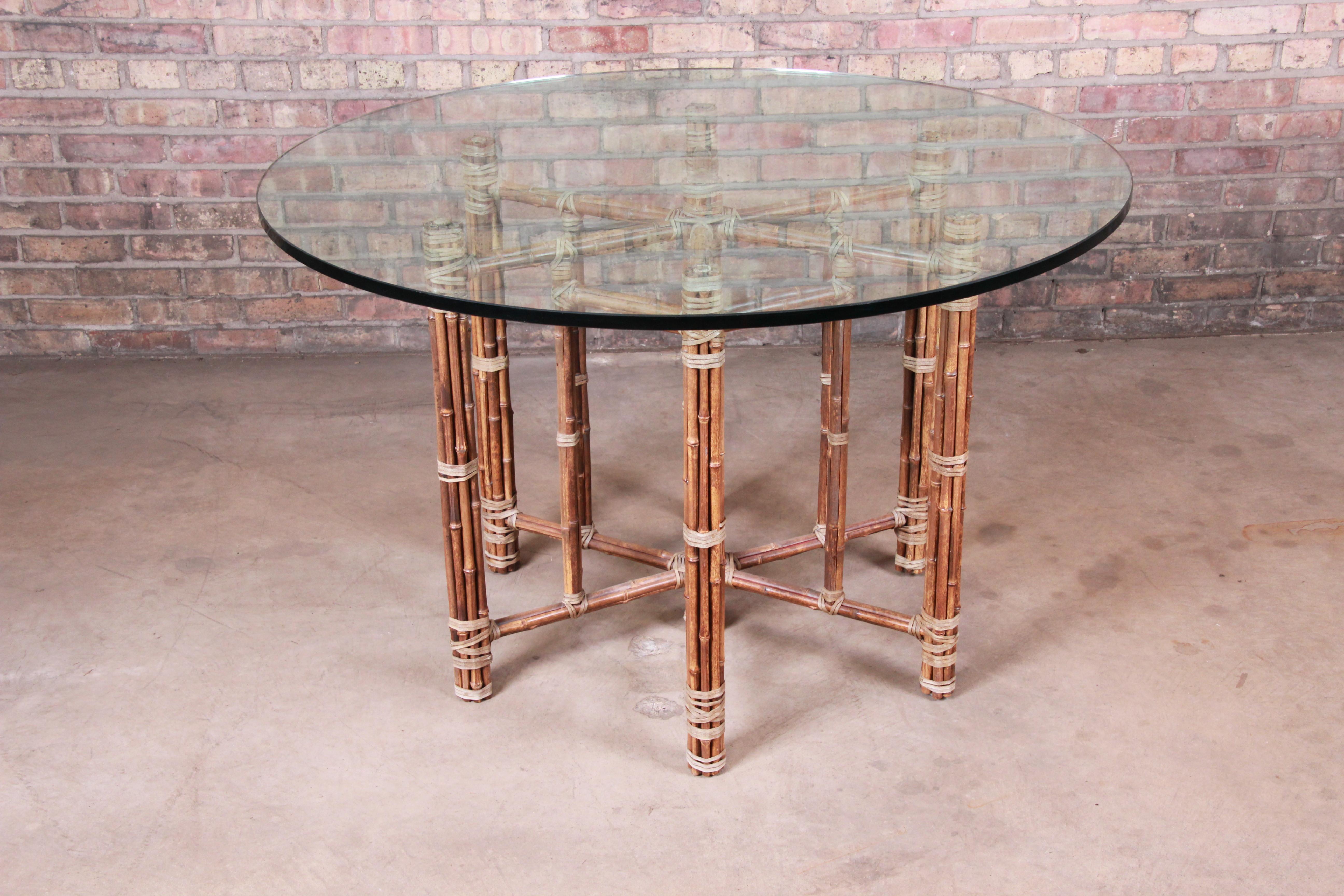 An exceptional midcentury organic modern round dining or center table

By McGuire

USA, circa 1970s

Base with steel inner core, wrapped in rattan and bamboo with raw hide leather wrapping. Thick glass top.

Measures: 48