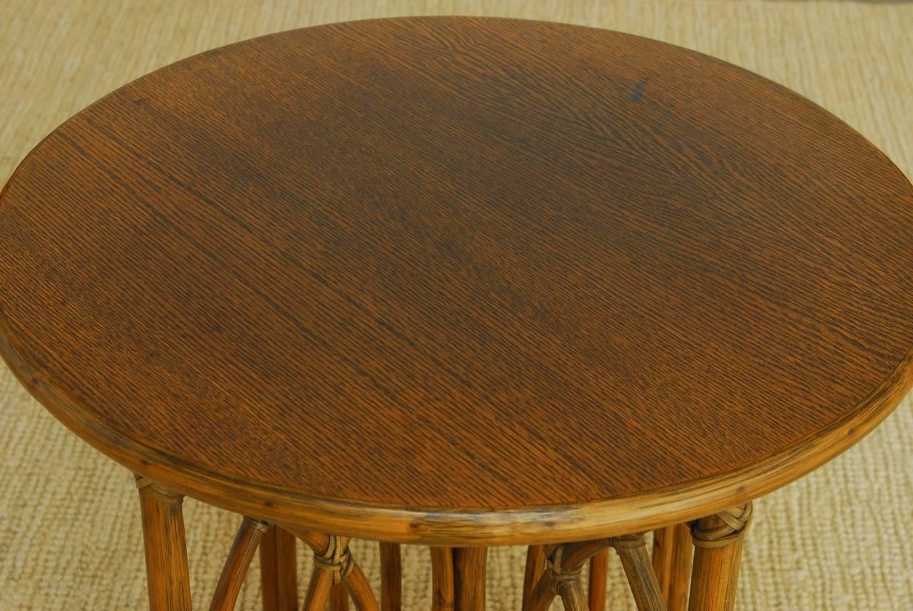 Distinctive McGuire organic modern side table or drink table constructed from bamboo and rattan with a round oak top. The support is designed from intersecting arches of rattan joined with leather rawhide strapping. The table has a rich finish that