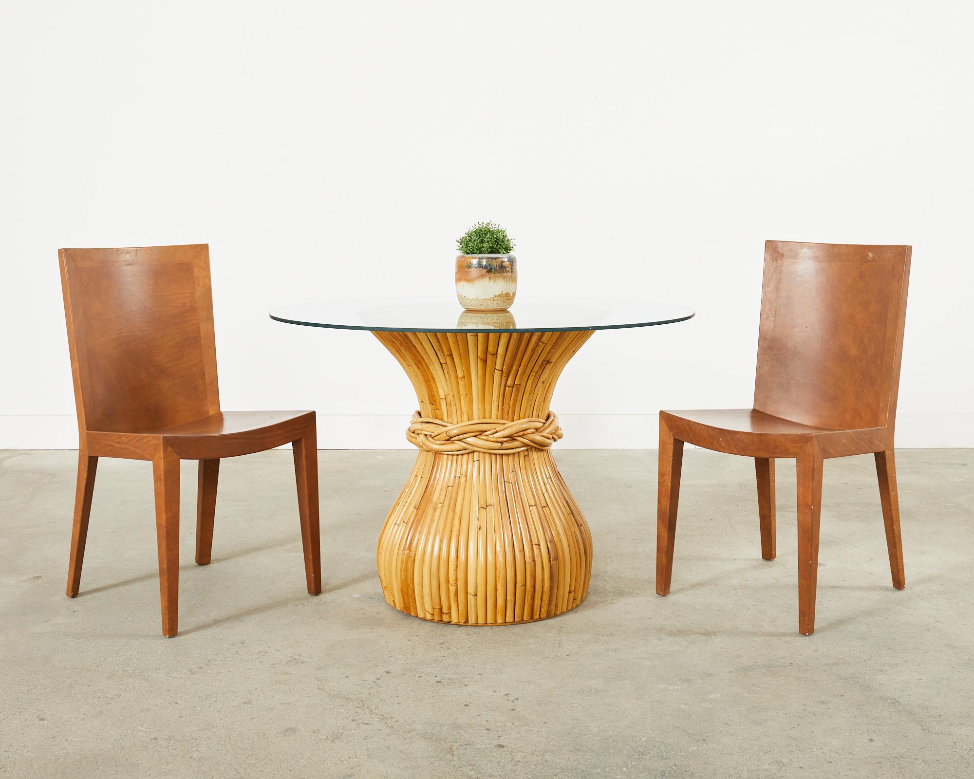Gorgeous hourglass form dining table or breakfast table made in the California coastal organic modern style by McGuire. The table features a waisted hourglass formed pedestal completely wrapped with split bamboo rattan poles. The middle of the table