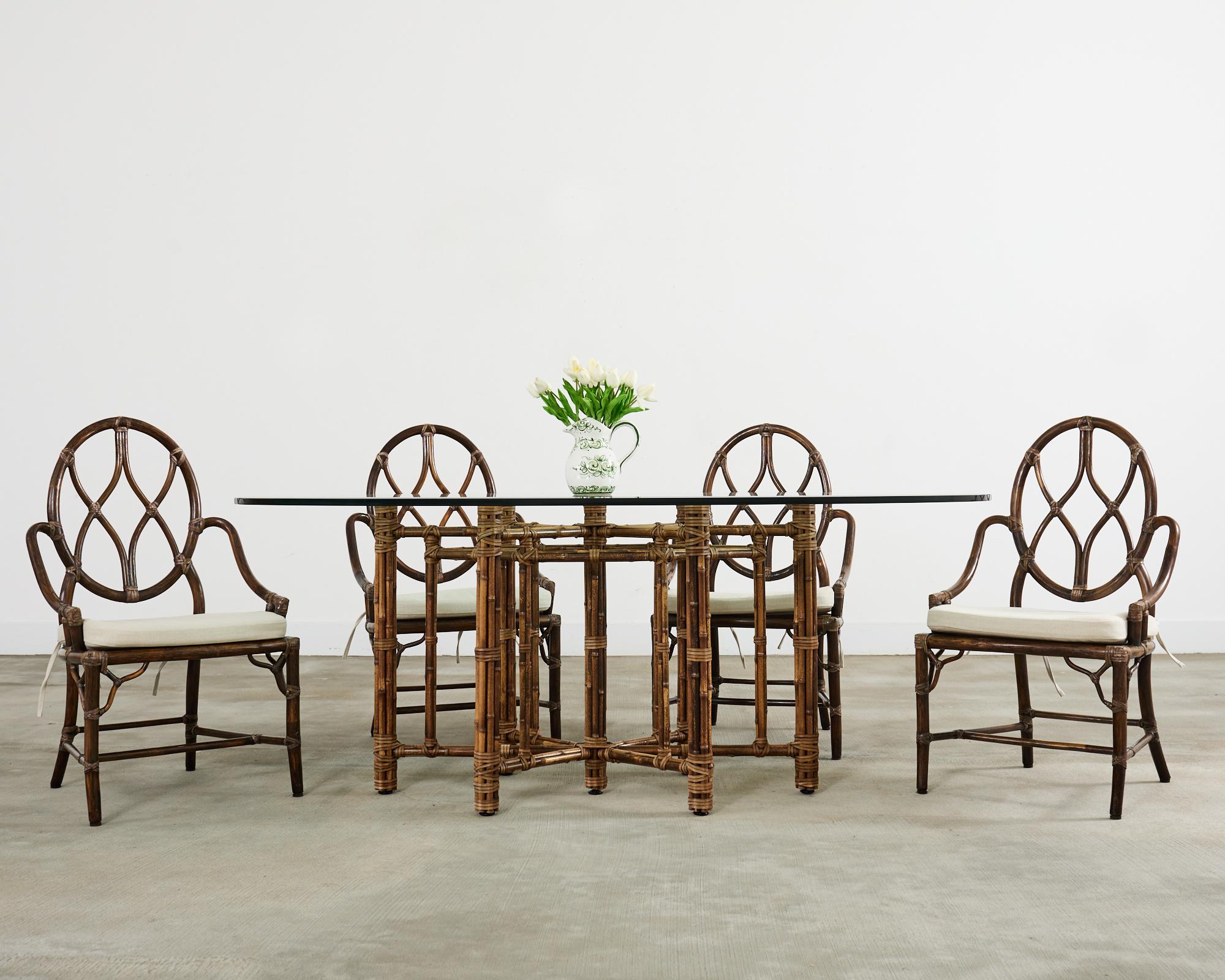 Stunning organic modern oval dining table made by McGuire. The table features an elongated hexagonal star shaped base topped with a thick pane of McGuire oval, beveled glass. The table features an elongated hexagonal star shaped iron base lacquered