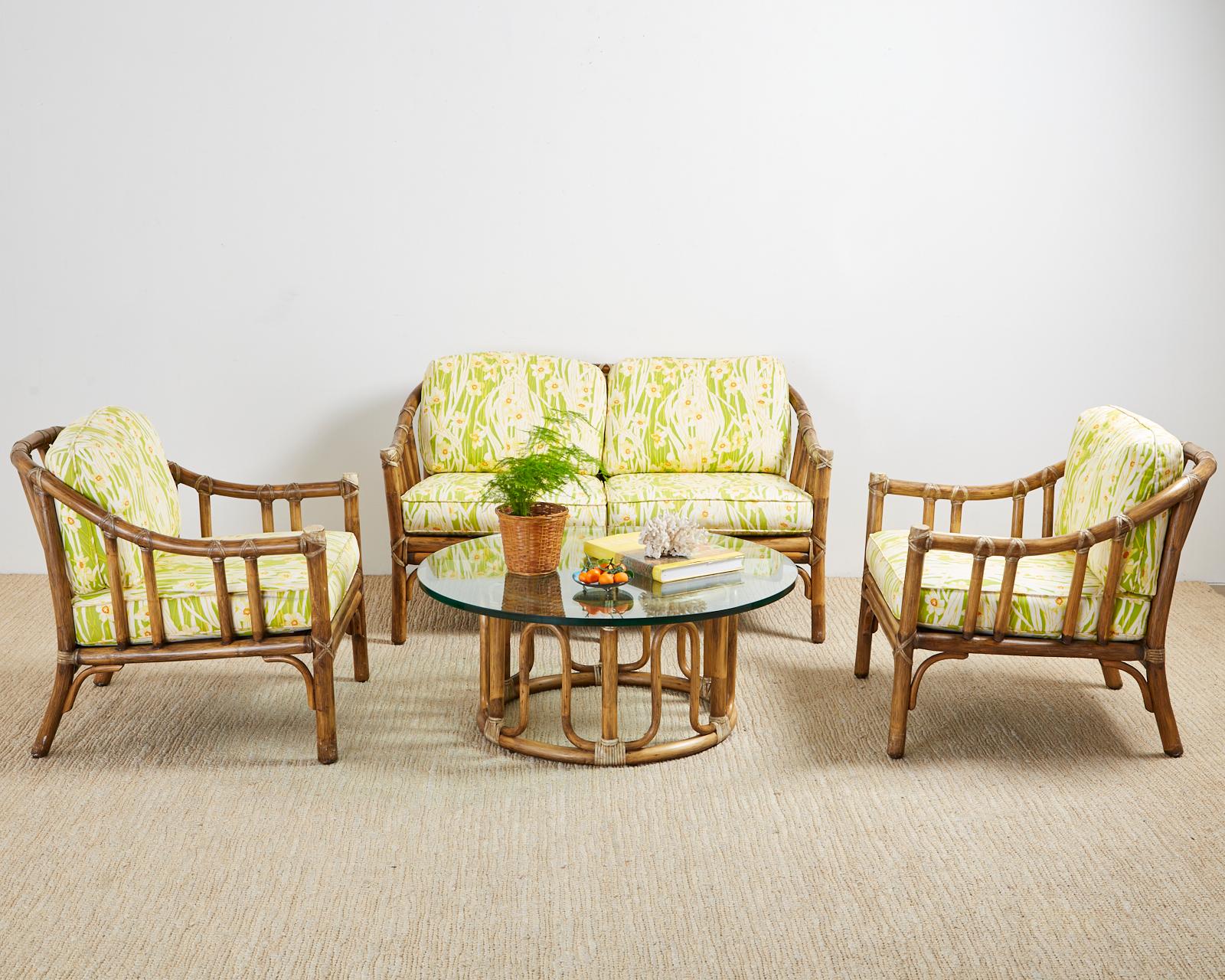 Genuine McGuire bamboo rattan settee or loveseat made in the California organic modern style. Features thick rattan poles lashed together with leather rawhide laces and topped with whimsical bright floral upholstery cushions. Excellent joinery and