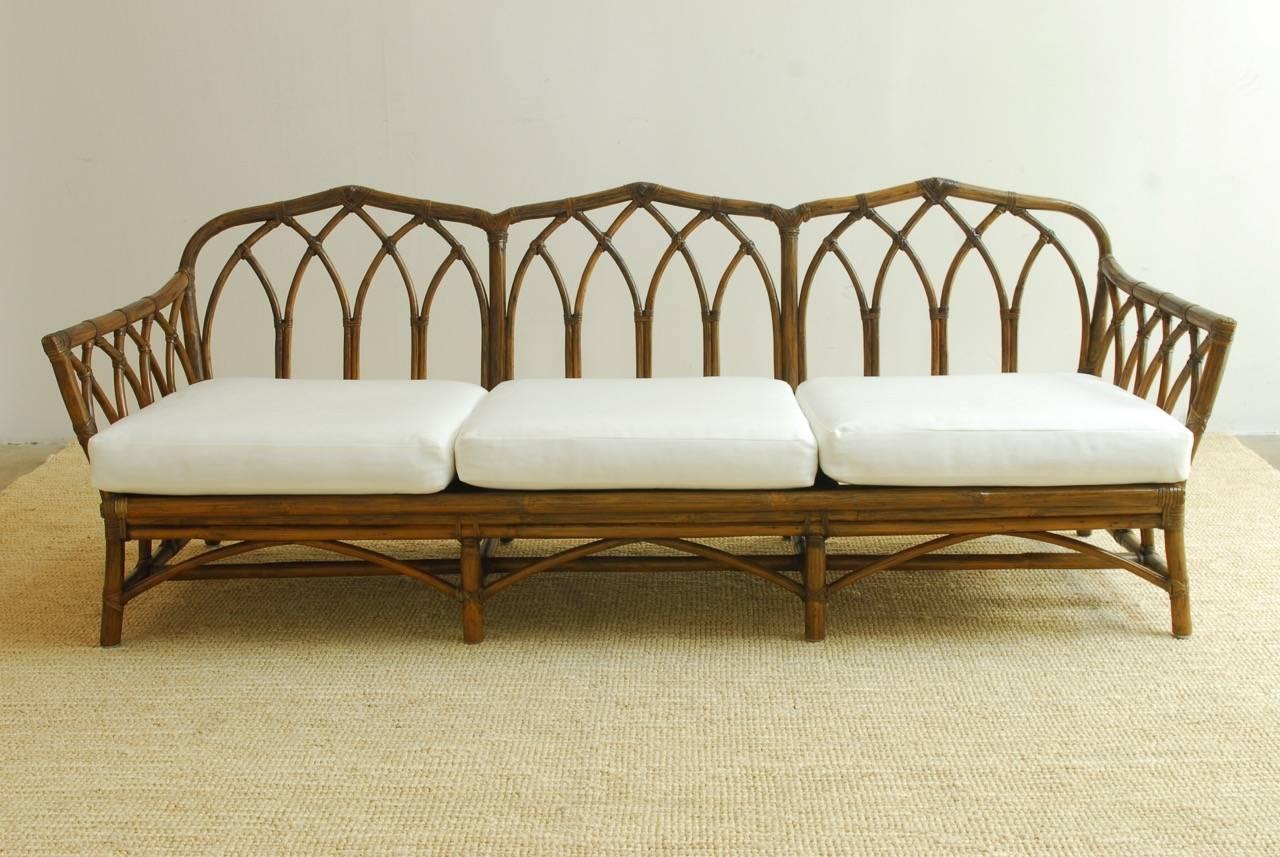 Exceptional organic modern bamboo and rattan sofa settee by McGuire Furniture Co. Beautifully hand-constructed frame of rattan arches gracefully intersecting and reinforced with leather rattan strapping. Newly upholstered seat cushions and pads of