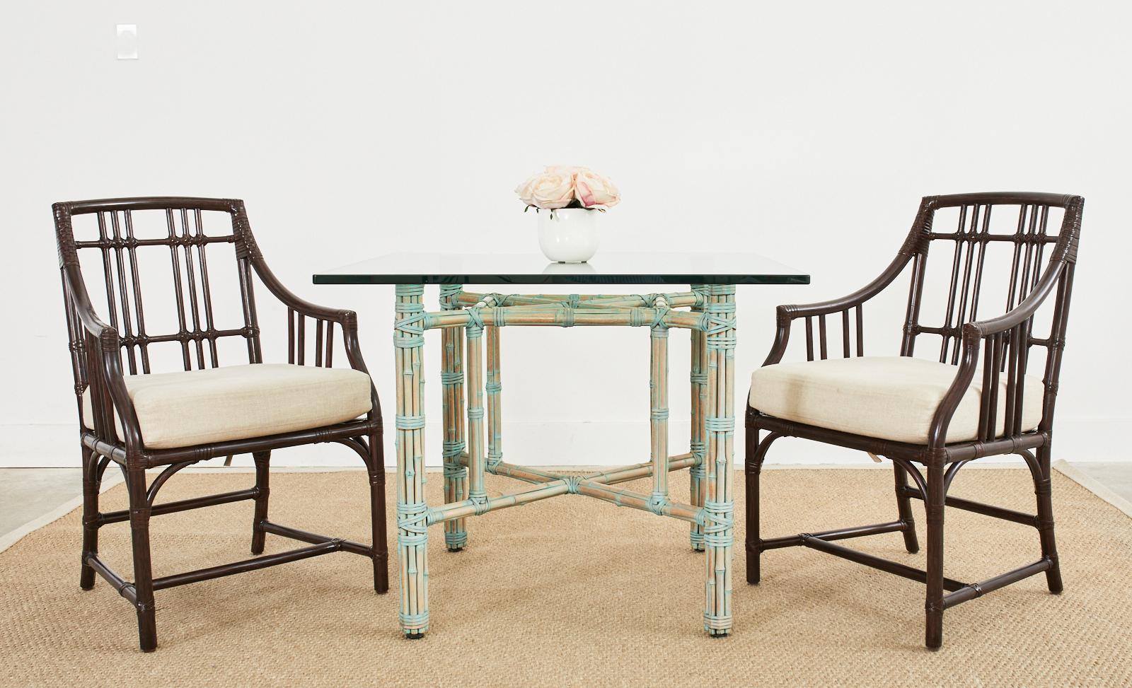 Genuine McGuire bamboo rattan dining table made in the California organic modern style. The table features a rare, bespoke glazed finish with a green verdigris patina tone. Crafted from an iron frame painted golden gate orange for authenticity and