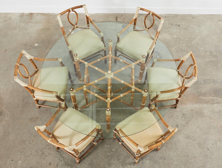 Gorgeous McGuire organic modern hexagonal base dining table featuring a large round glass top. This is an early McGuire model #MCBA17 crafted with a geometric iron frame hand-wrapped with blonde toned bamboo poles. The bamboo is lashed together with