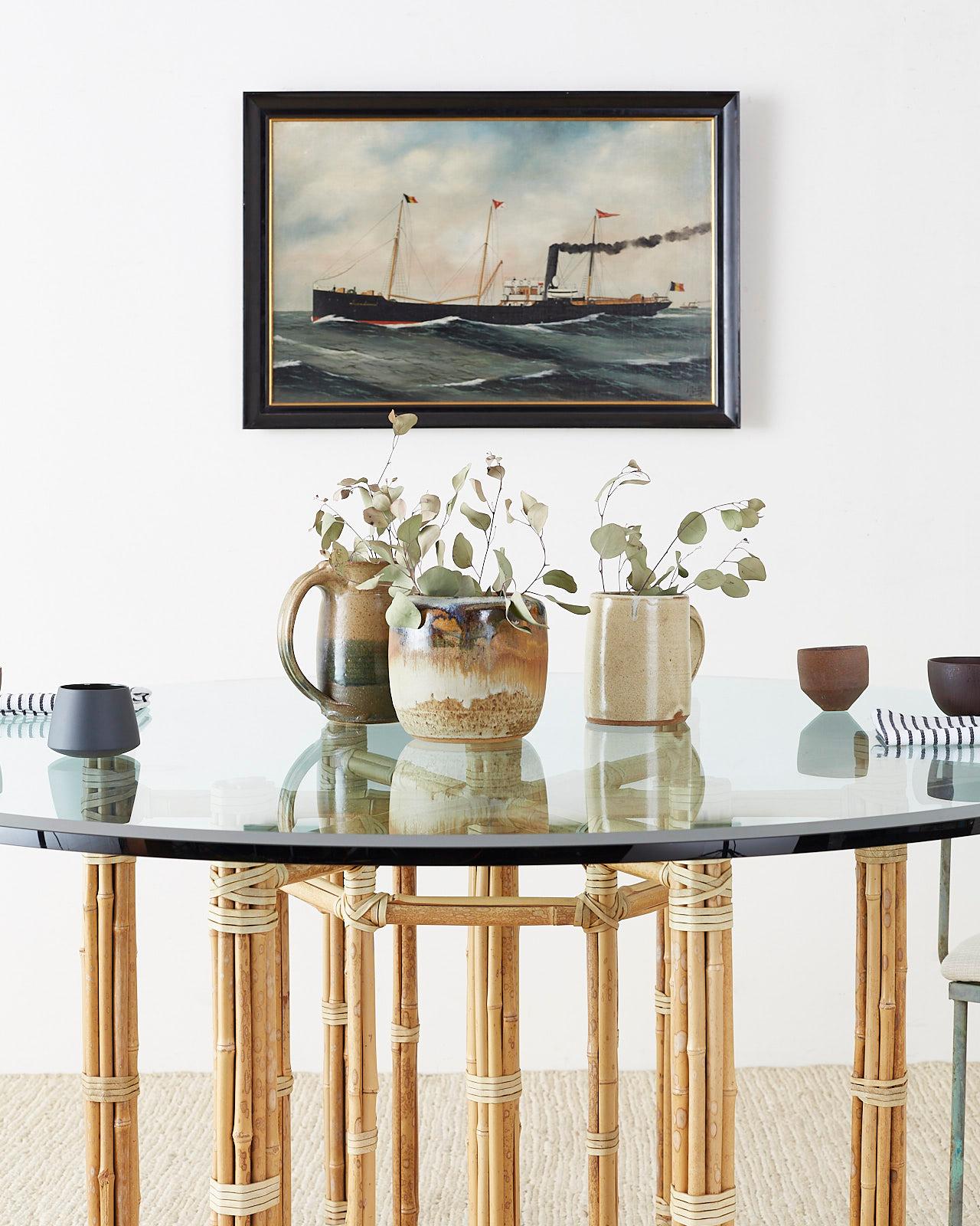 Genuine McGuire organic modern round dining table. Featuring an iron frame wrapped with bamboo rattan poles. The bamboo rattan has a light blonde tone and is lashed together with a cream colored leather rawhide strapping. The frame has a seven leg