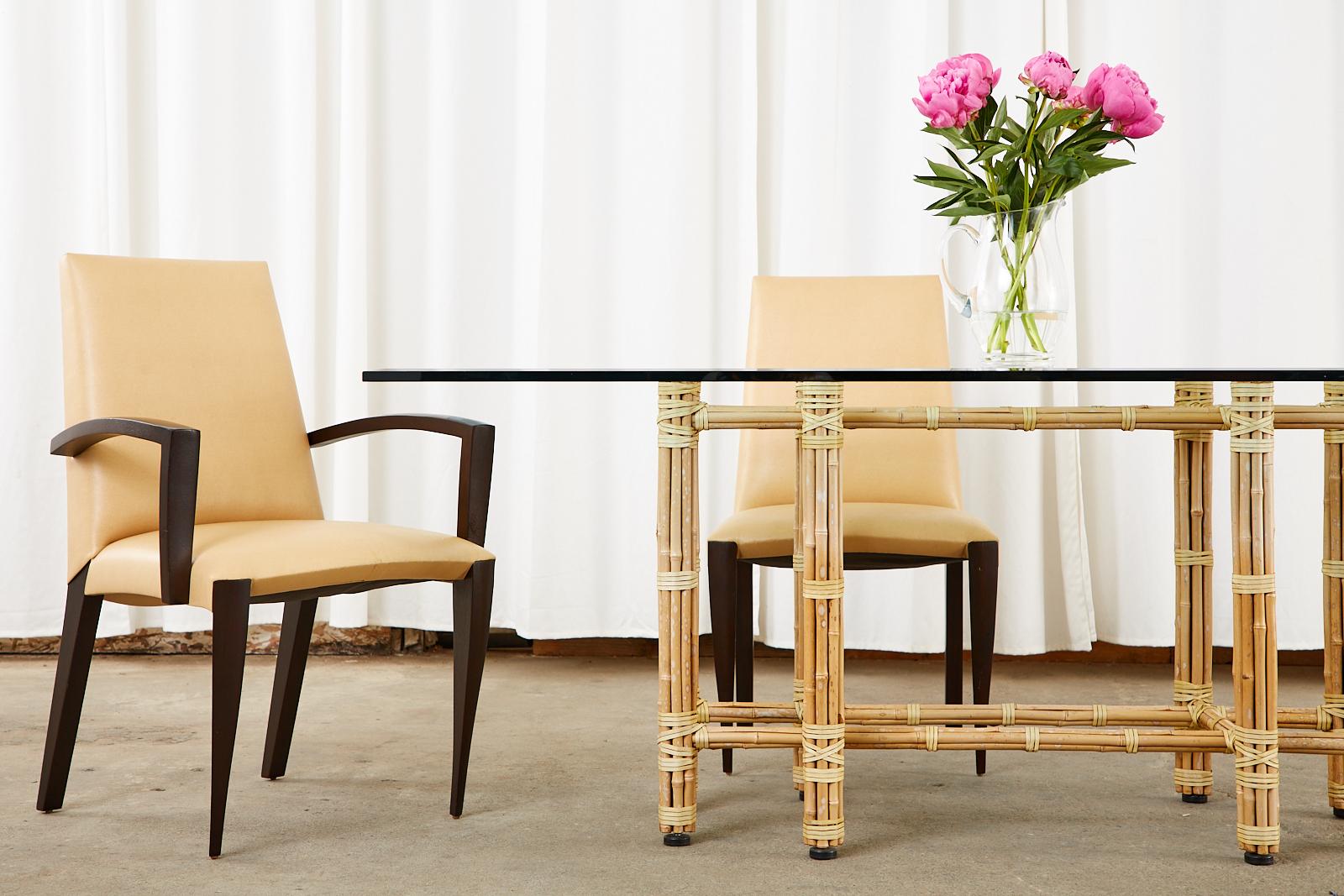 Stunning blonde bamboo and glass rectangular dining table made by McGuire (Model# MCBA22). Designed by John McGuire the table features an iron frame covered with bamboo poles lashed together with leather rawhide laces. Topped with a thick pane of