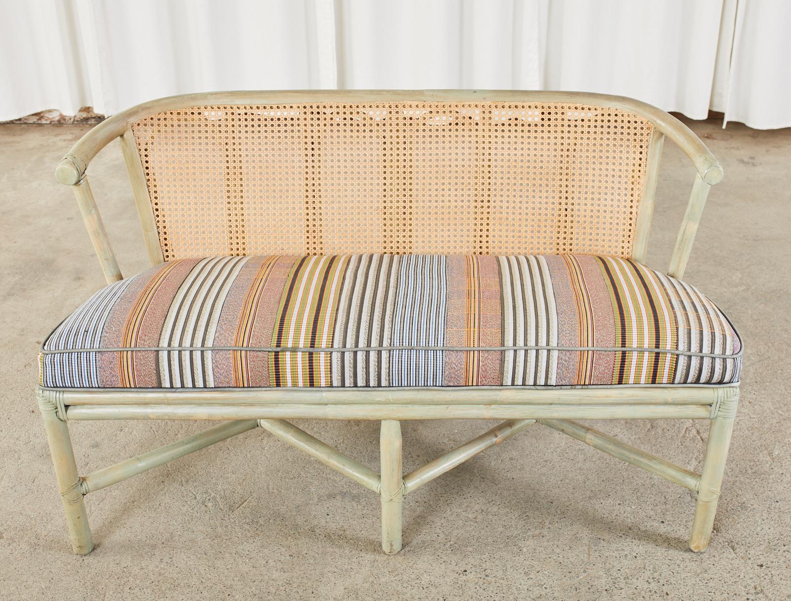 Lacquered organic modern style rattan bench seat or settee by McGuire. The small bench features a rattan frame that has been lacquered with a caned back rest. Lashed together with leather rawhide laces on the exposed joints. The open seat is fitted