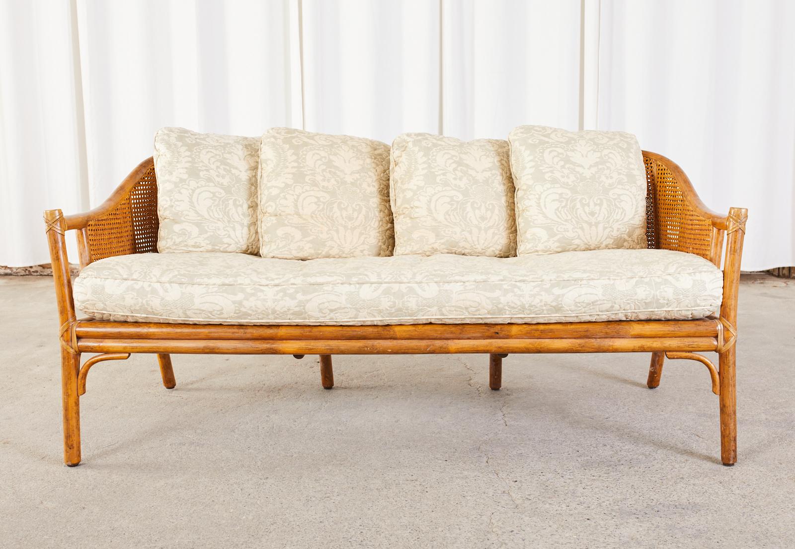 Genuine McGuire sofa settee made in the California organic modern style. The sofa features a bamboo rattan pole frame with double caned walls. Lashed together on all exposed joints with leather rawhide laces. Vintage upholstery includes a large