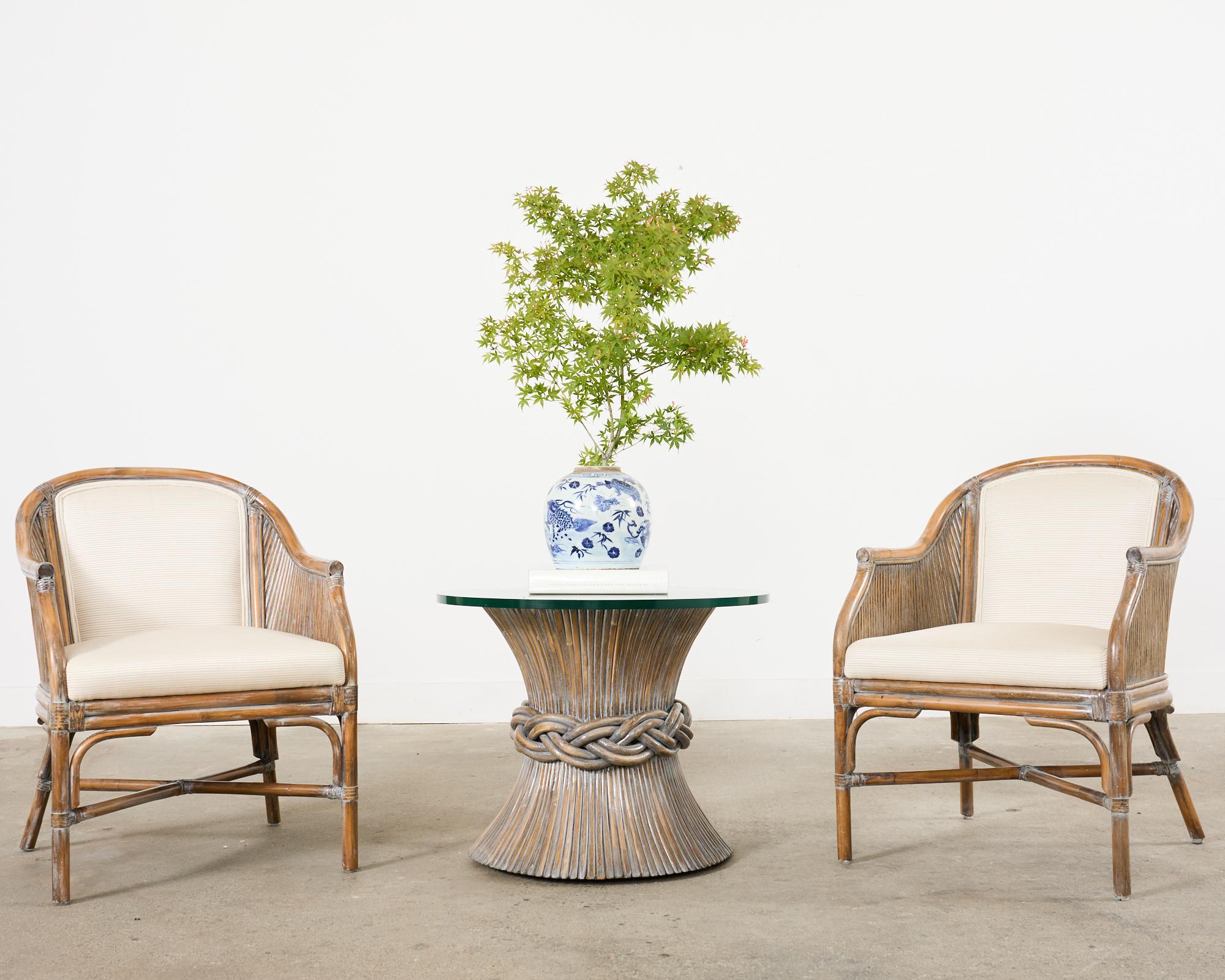 Table à cocktail ou table basse iconique en bambou rotin, réalisée dans le style moderne organique côtier californien par McGuire. La table présente une forme de sablier en rotin fagoté avec une taille tressée surmontée d'une vitre ronde en verre