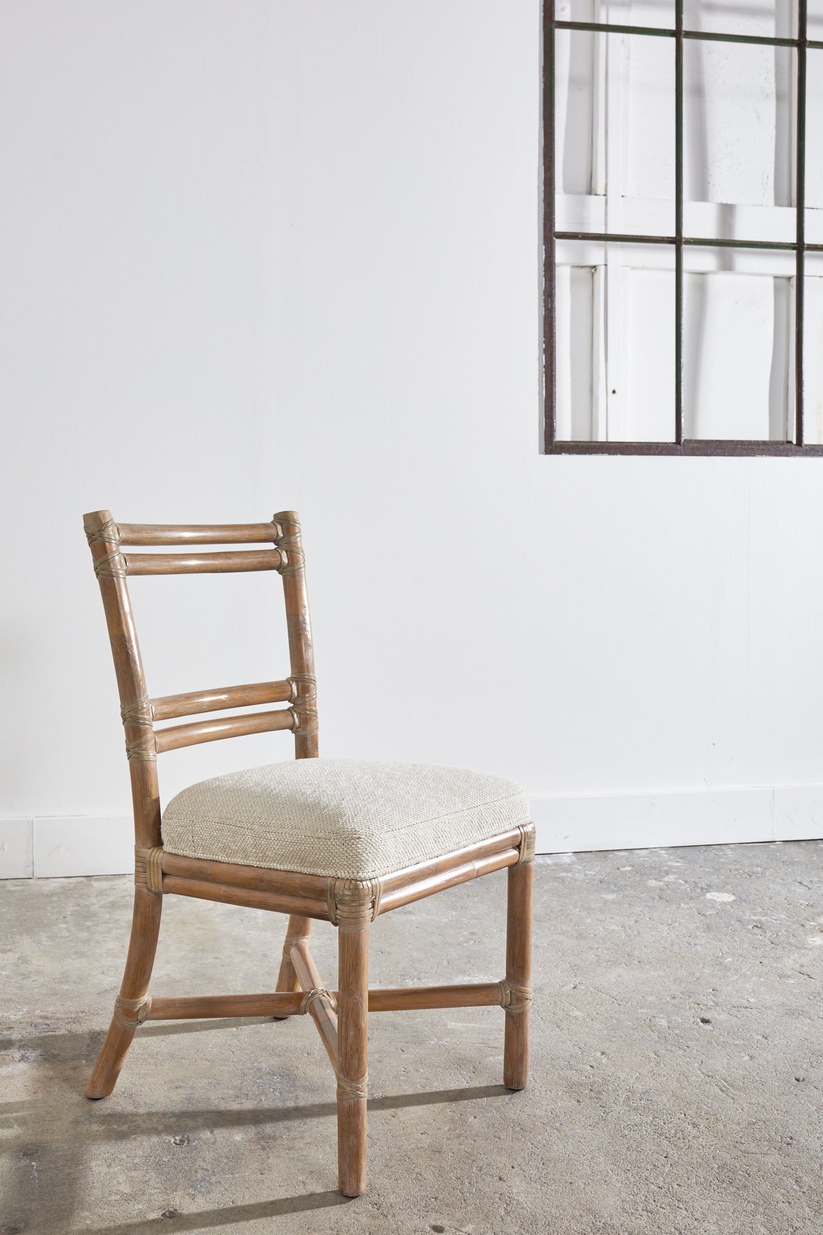 Stylish rattan ladder back style chair made in the California coastal manner by McGuire San Francisco, CA. The chair features thick rattan poles lashed together with leather rawhide laces. The rattan has a subtle cerused or glazed finish to give it