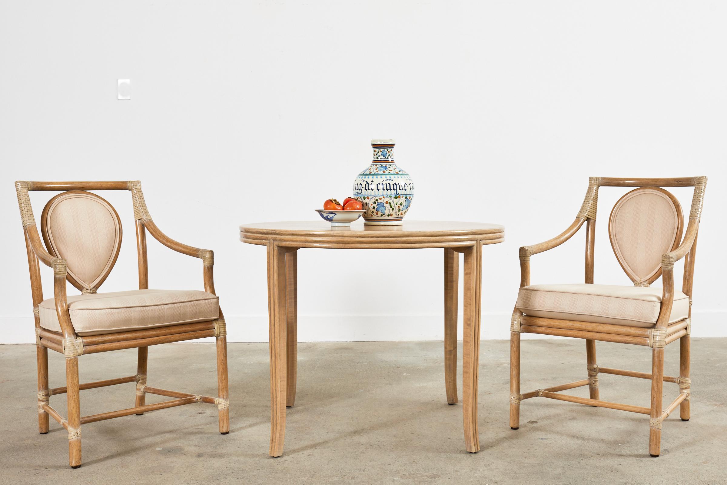 Gorgeous round rattan and oak breakfast dining table or center table made in the coastal organic modern style by McGuire. The elegant table features an oak frame veneered on the sides and legs with split rattan poles giving the edges a reeded