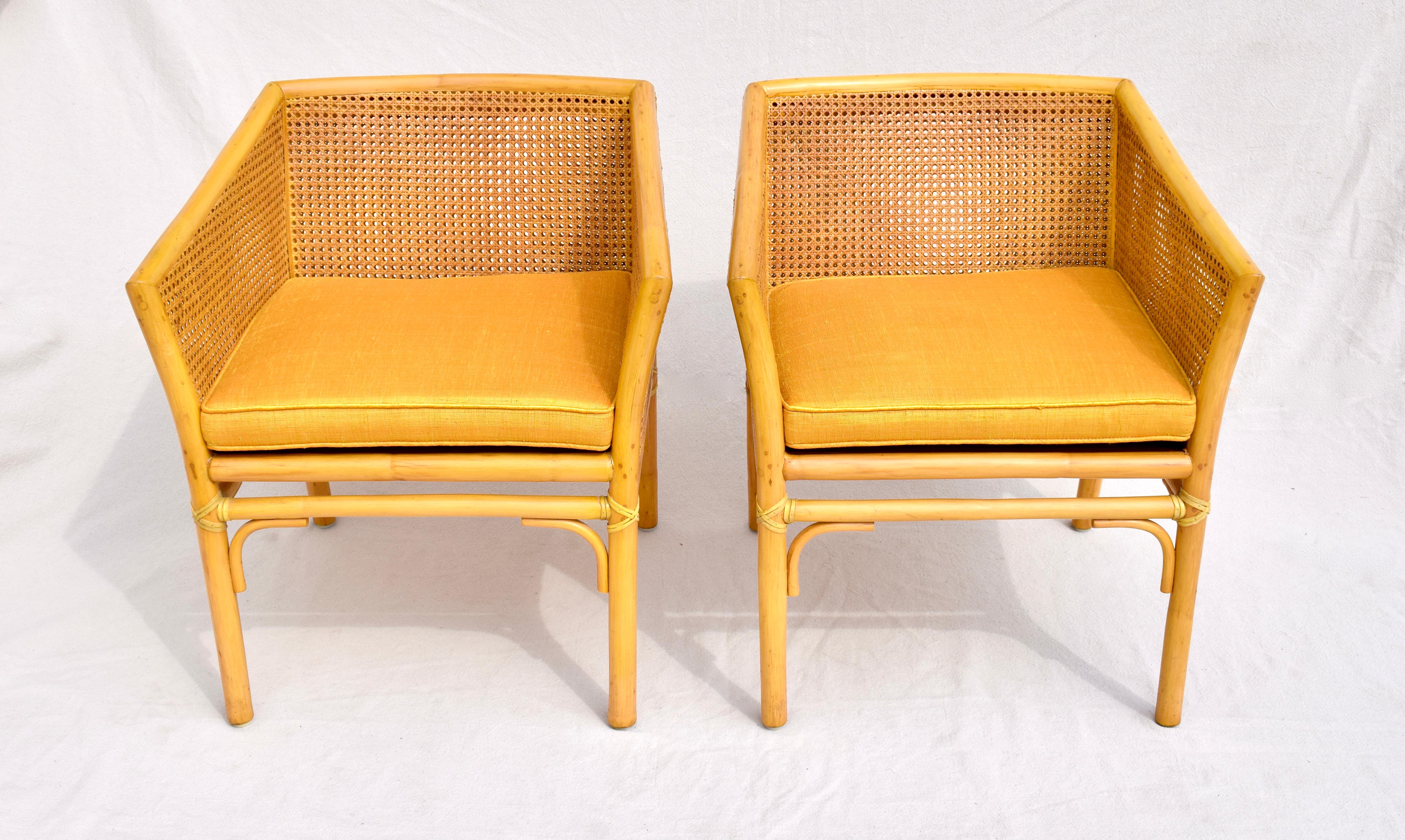 A matching pair of organic modern McGuire of San Francisco double caned Rattan chairs. Features include custom sunflower goldenrod finish & raw silk cushions, bamboo rattan pole frame construction with laced rawhide exposed at every point of