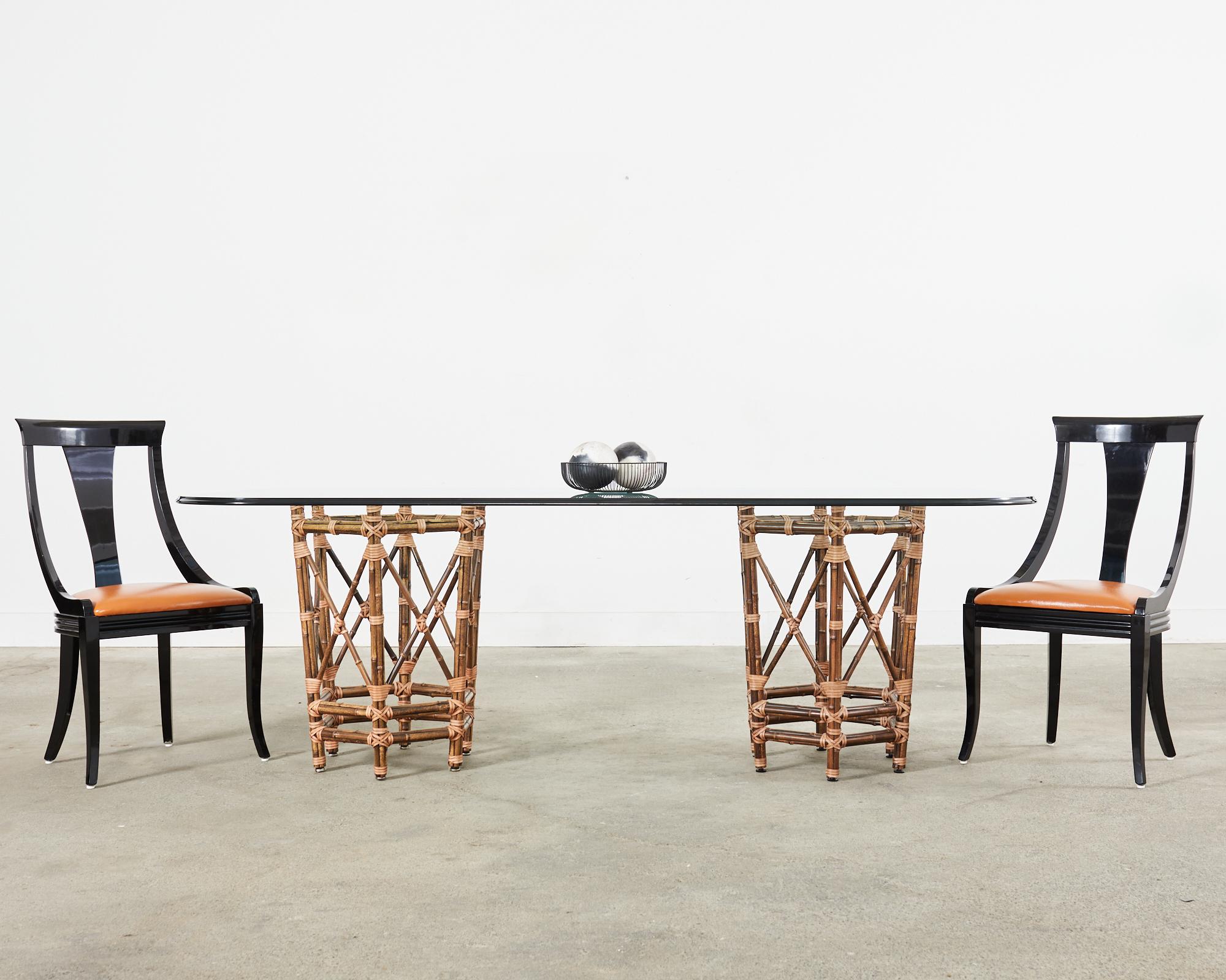 Large bespoke dining table made in the California coastal organic modern style by McGuire. The table features double pedestal basket shaped supports crafted from iron. The iron frames are painted golden gate orange for authenticity and covered with